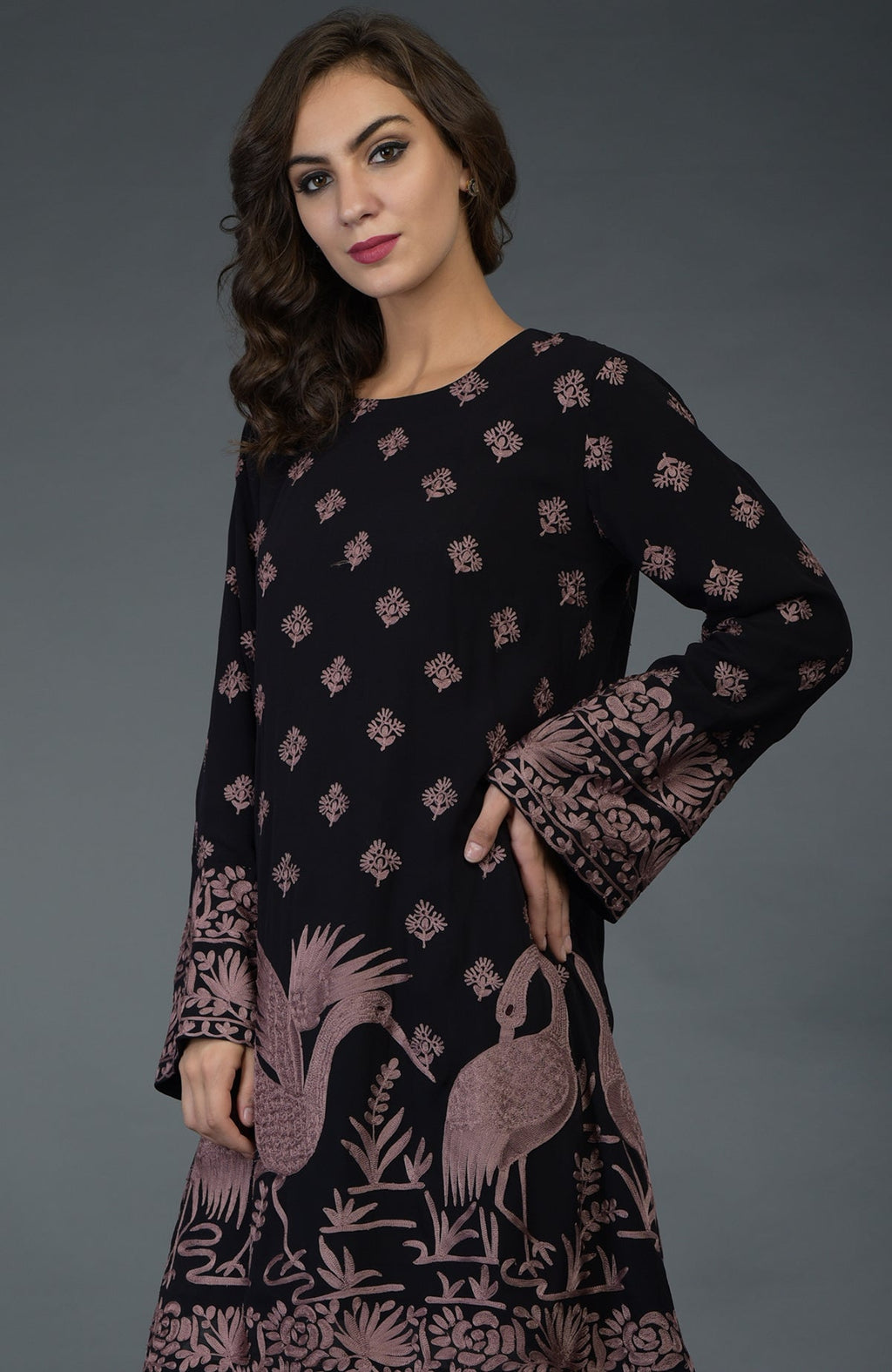 A woman models a black tunic with mauve Parsi embroidery and crane motifs.