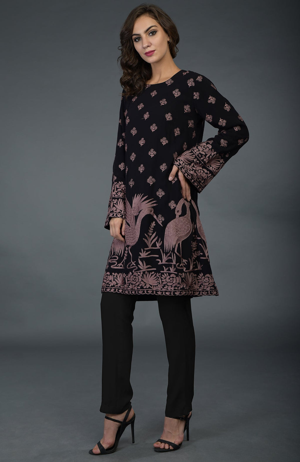 A woman models a black tunic with mauve Parsi embroidery and black pants.