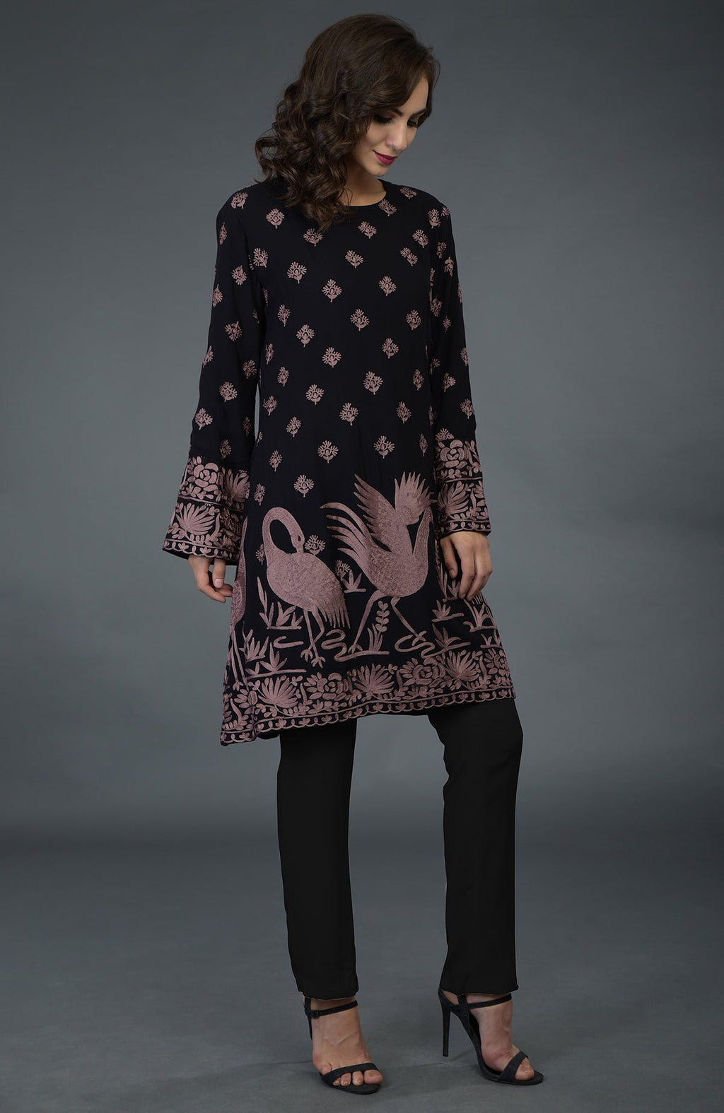 A woman models a black tunic with mauve Parsi embroidery and black pants.