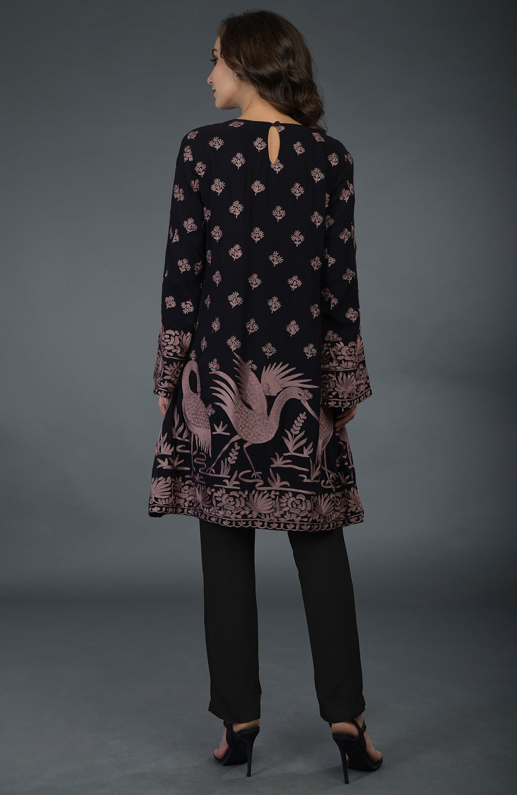 A woman models a black tunic with mauve Parsi embroidery and matching pants.