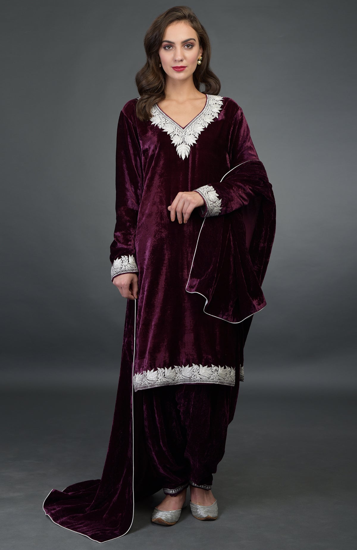 A woman models a dark plum silk-velvet Patiala salwar suit with silver Tilla embroidery.