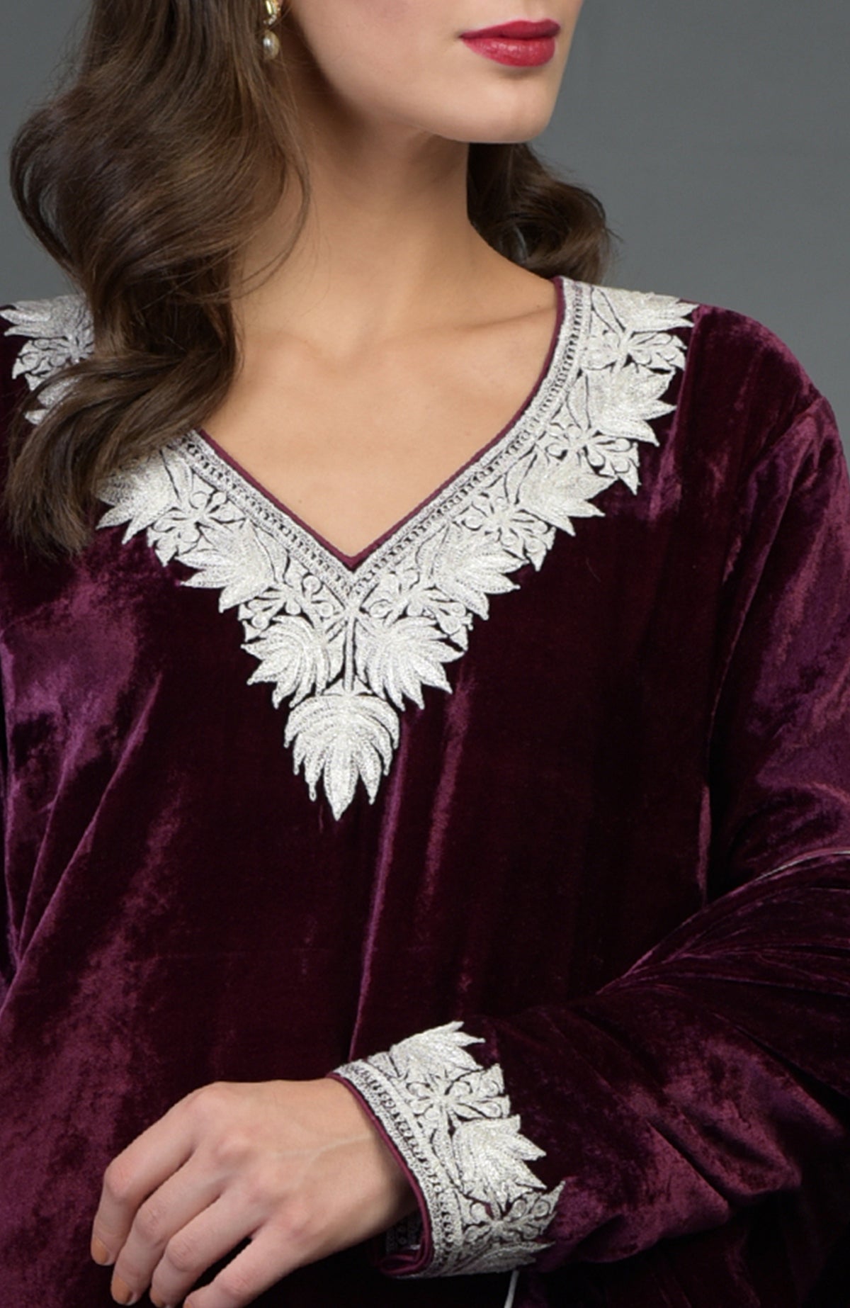 A woman models a dark plum velvet salwar suit with silver tilla embroidery.