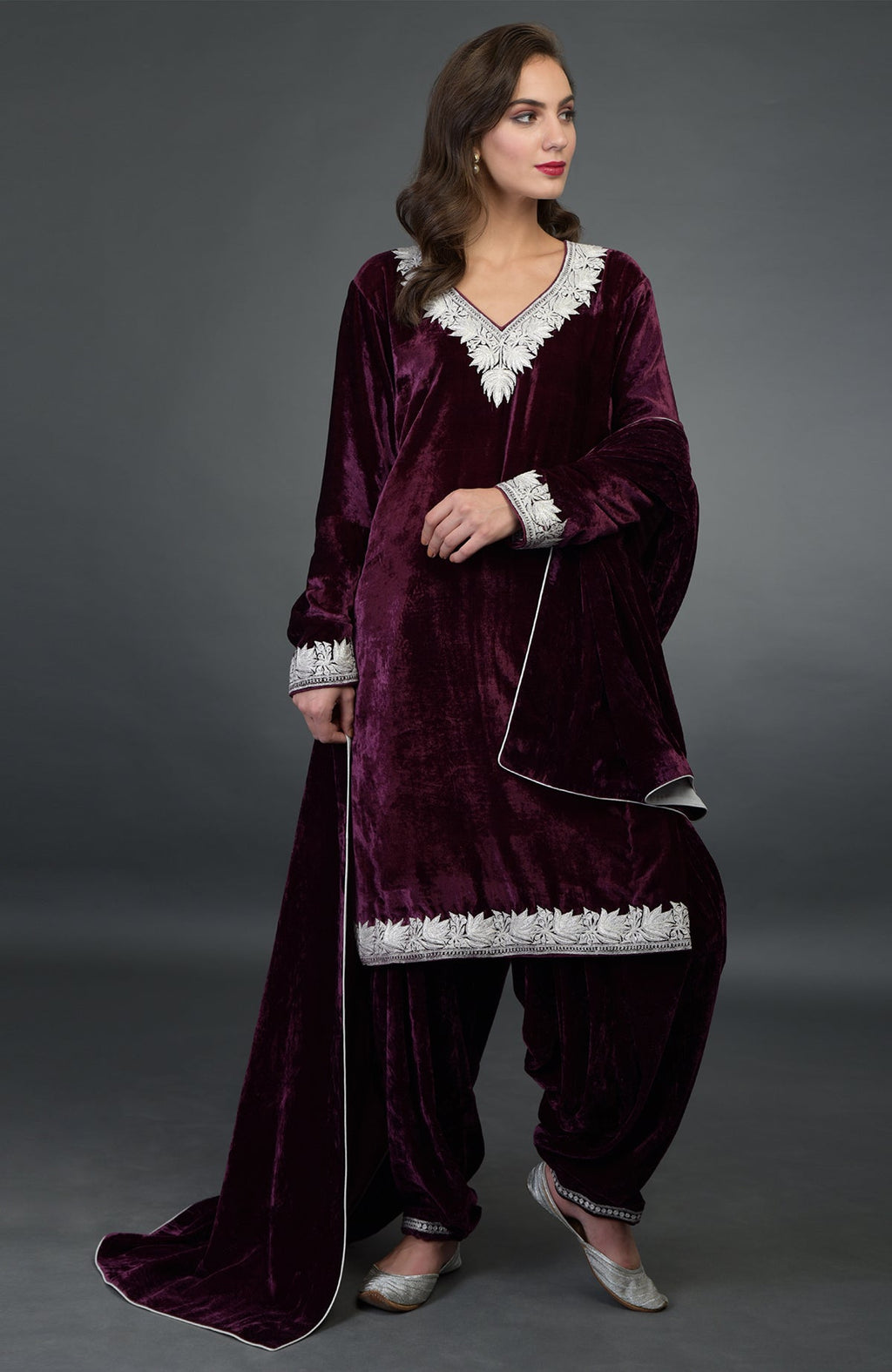 A woman models a dark plum silk-velvet Patiala salwar suit with silver Tilla embroidery.