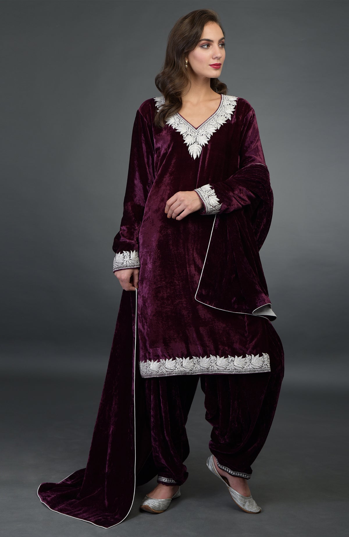 A woman models a dark plum silk-velvet Patiala salwar suit with silver Tilla embroidery.