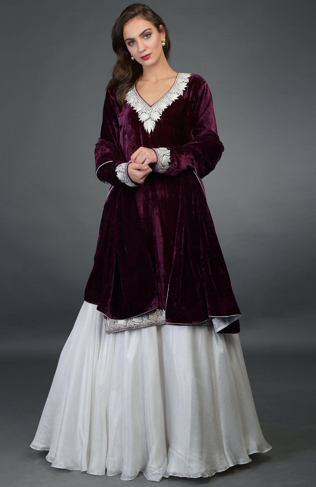 A woman models a plum velvet kurta with silver embroidery and a white skirt.