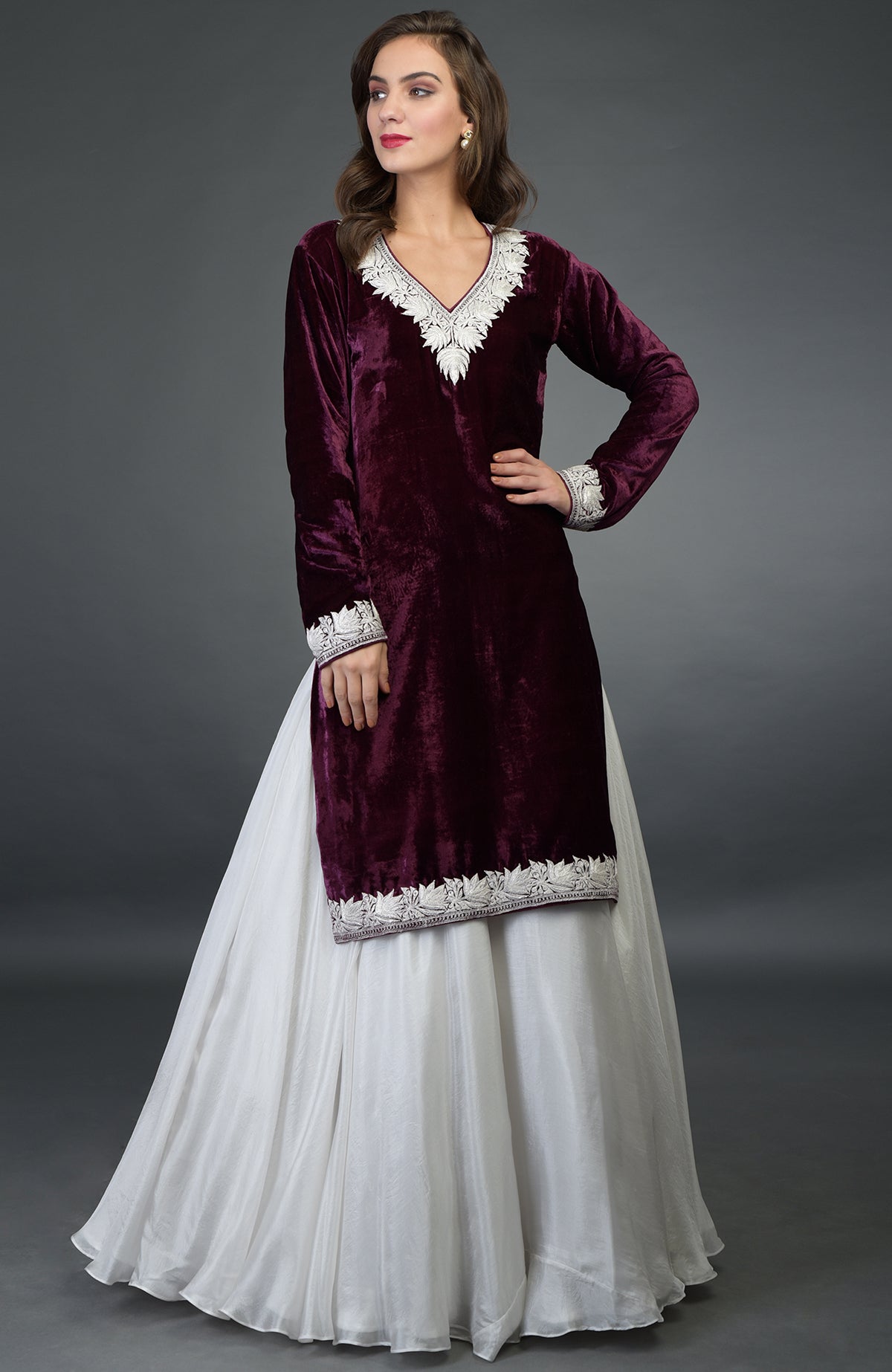 A woman models a plum velvet kurta with silver embroidery and a white skirt.