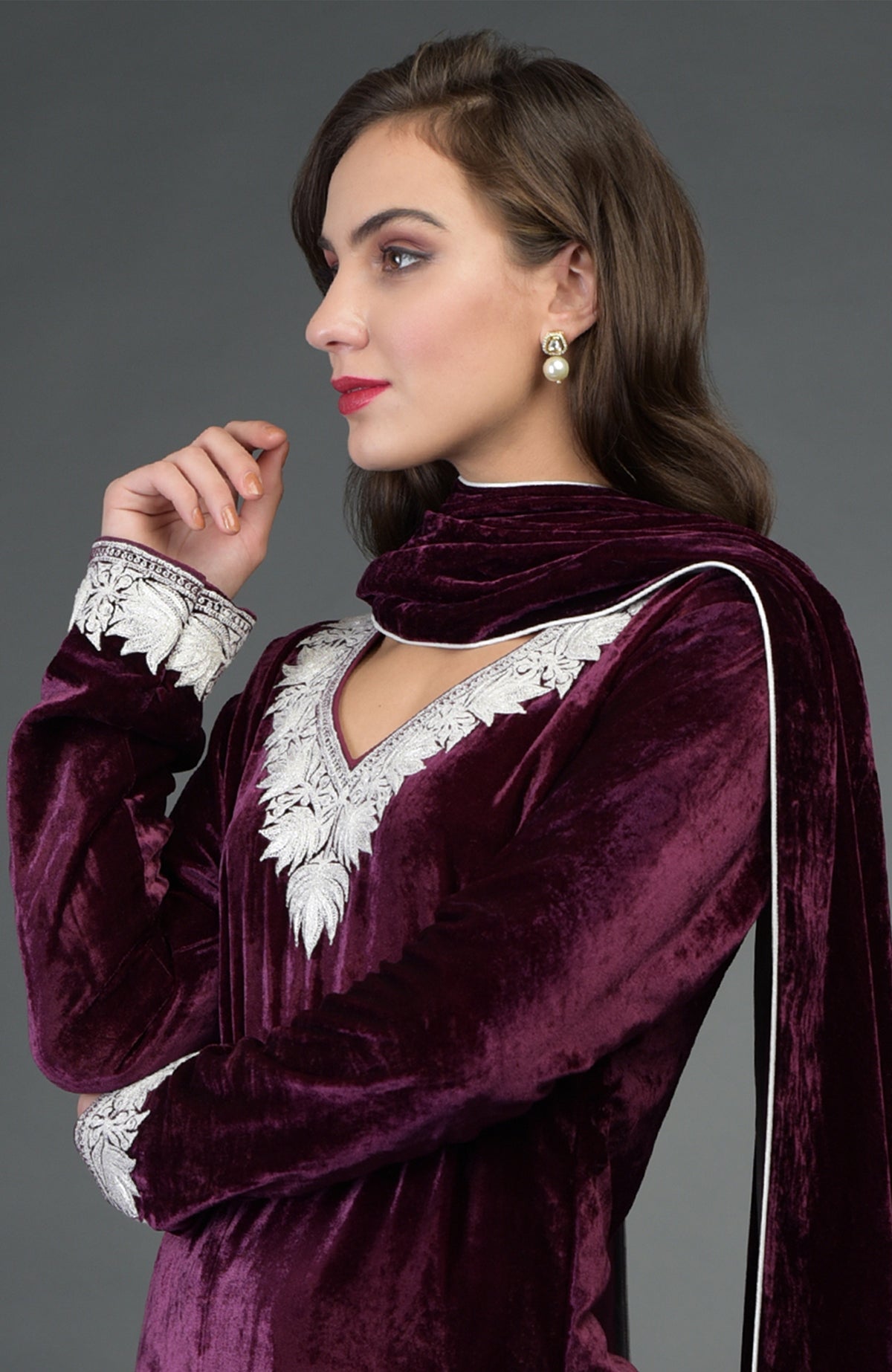 A woman models a plum velvet kurta with silver tilla embroidery and a matching dupatta.