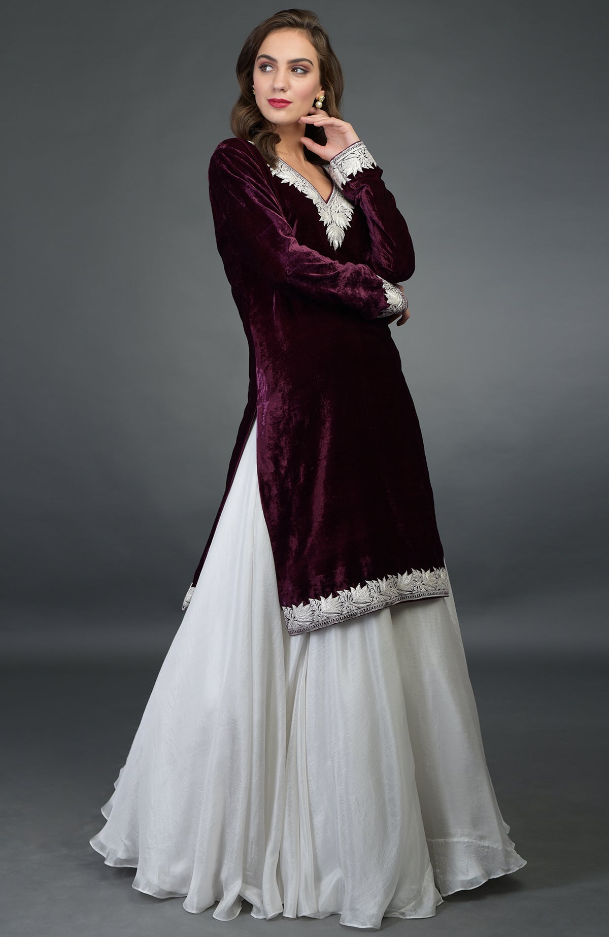 A woman models a plum velvet kurta with silver embroidery over a white skirt.