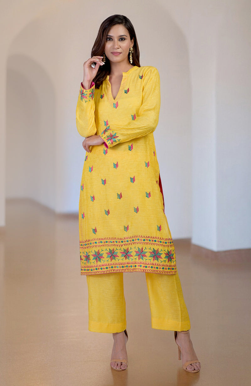 A woman models a yellow Phulkari embroidered kurta set with a V-neckline.