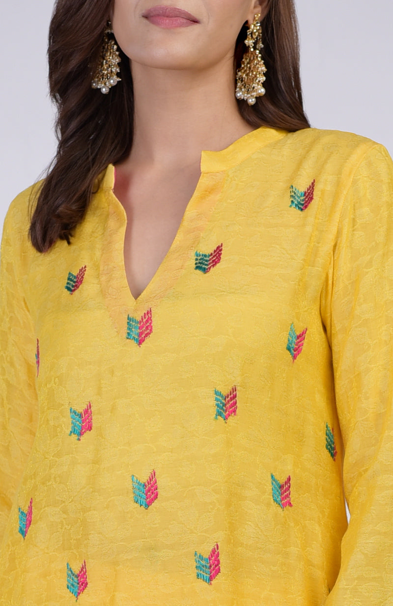 Yellow kurta with colorful Phulkari embroidery and a V-neckline.