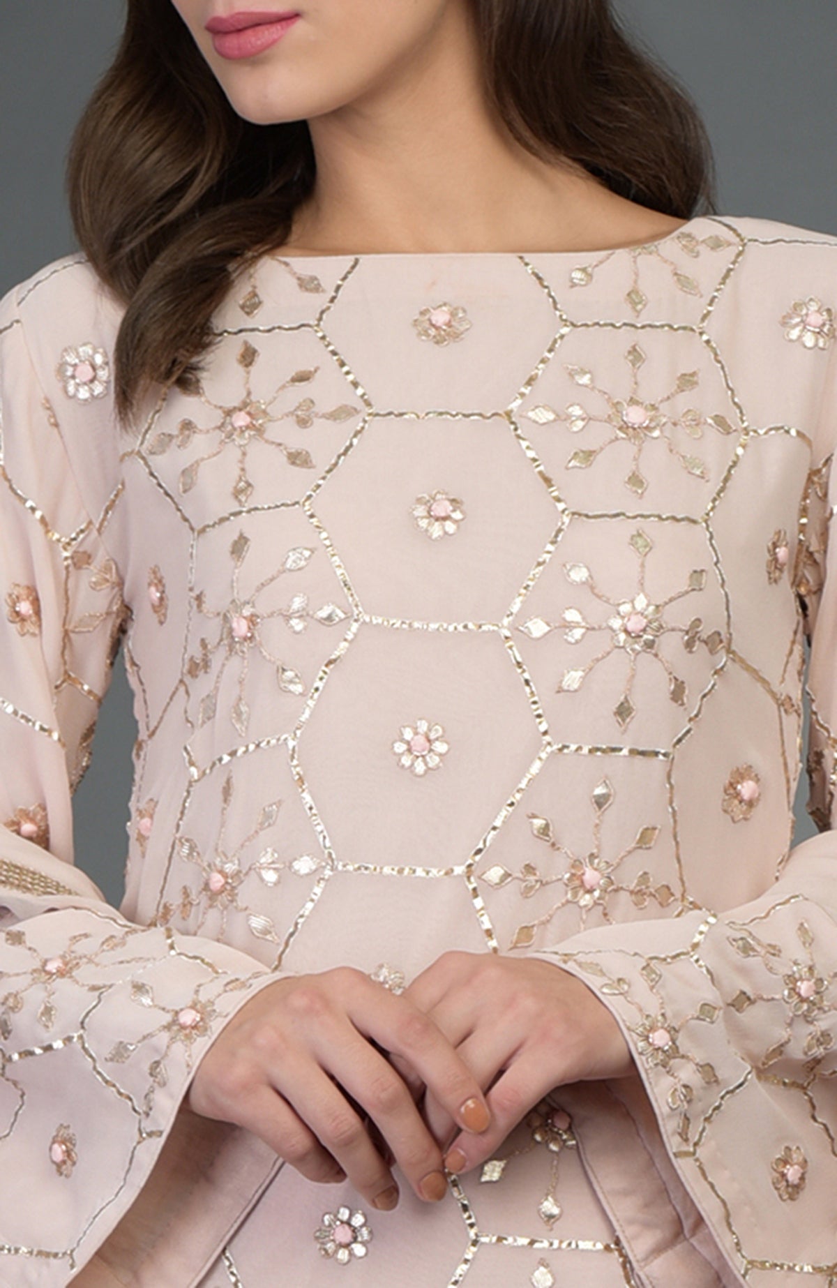 A woman models a nude pink suit with rose gold gota patti work.
