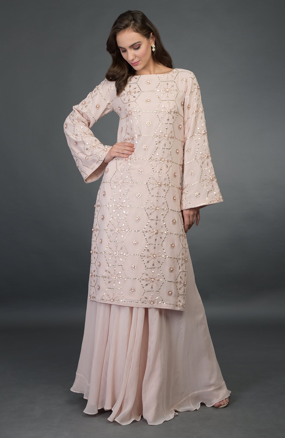 A woman models a nude pink suit with rose gold gota patti work.