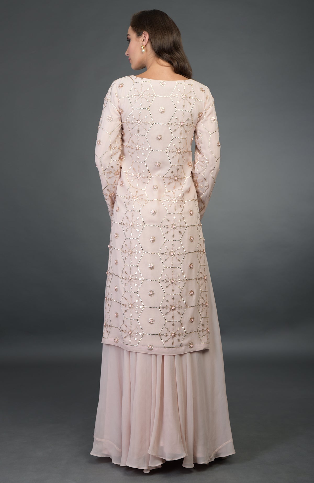 A woman models a nude pink suit with rose gold gota patti work.