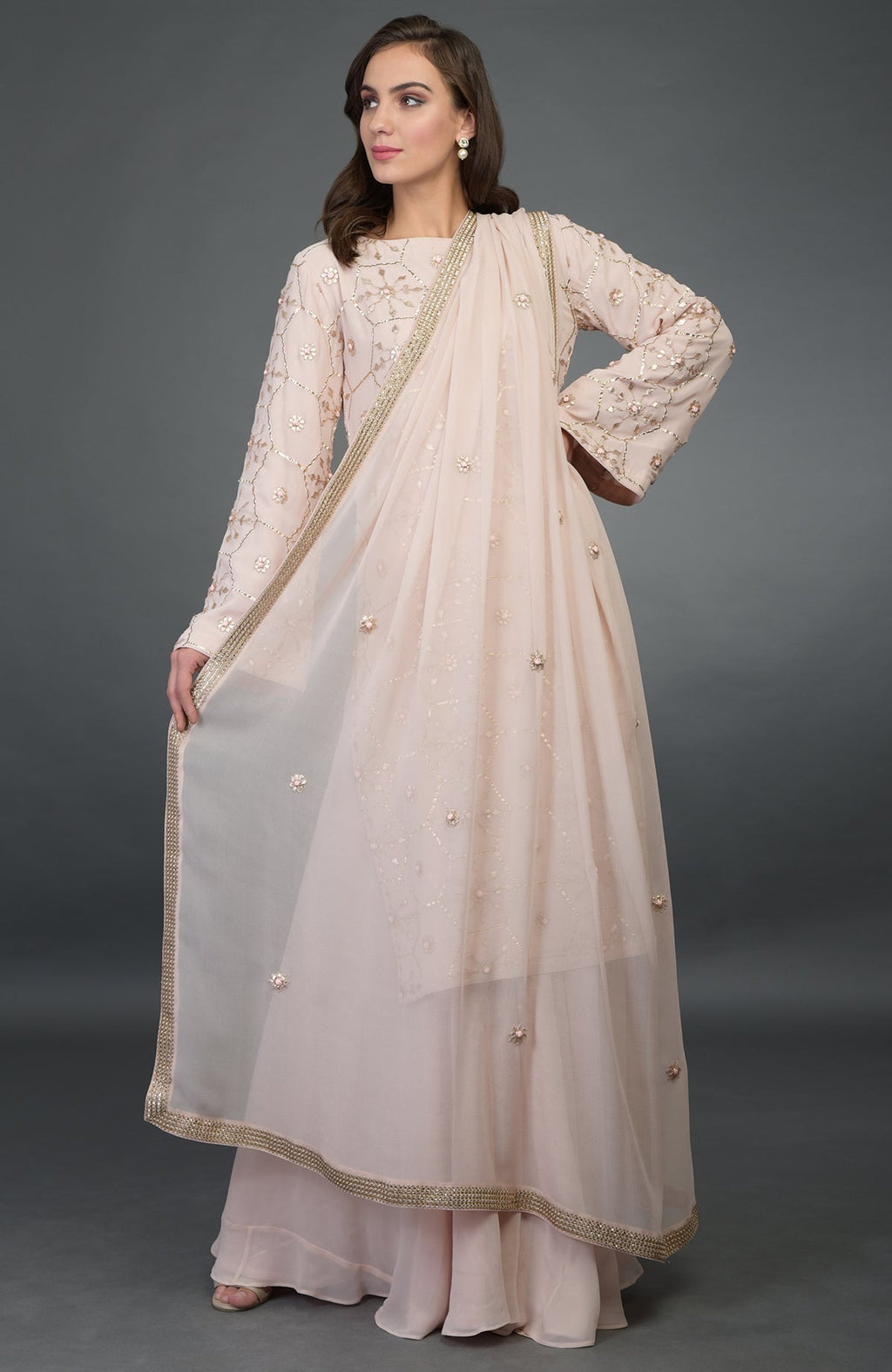A woman models a nude pink suit with rose gold embroidery and a matching dupatta.