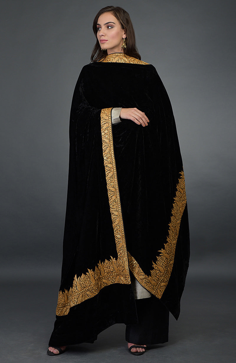 Woman in black velvet dupatta with gold embroidery over a beige kurta and black palazzo.