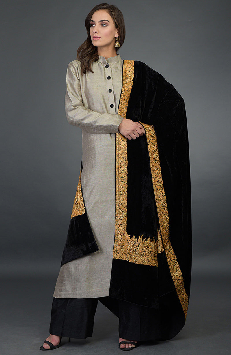 A woman models a beige raw silk palazzo suit with a black velvet embroidered dupatta.