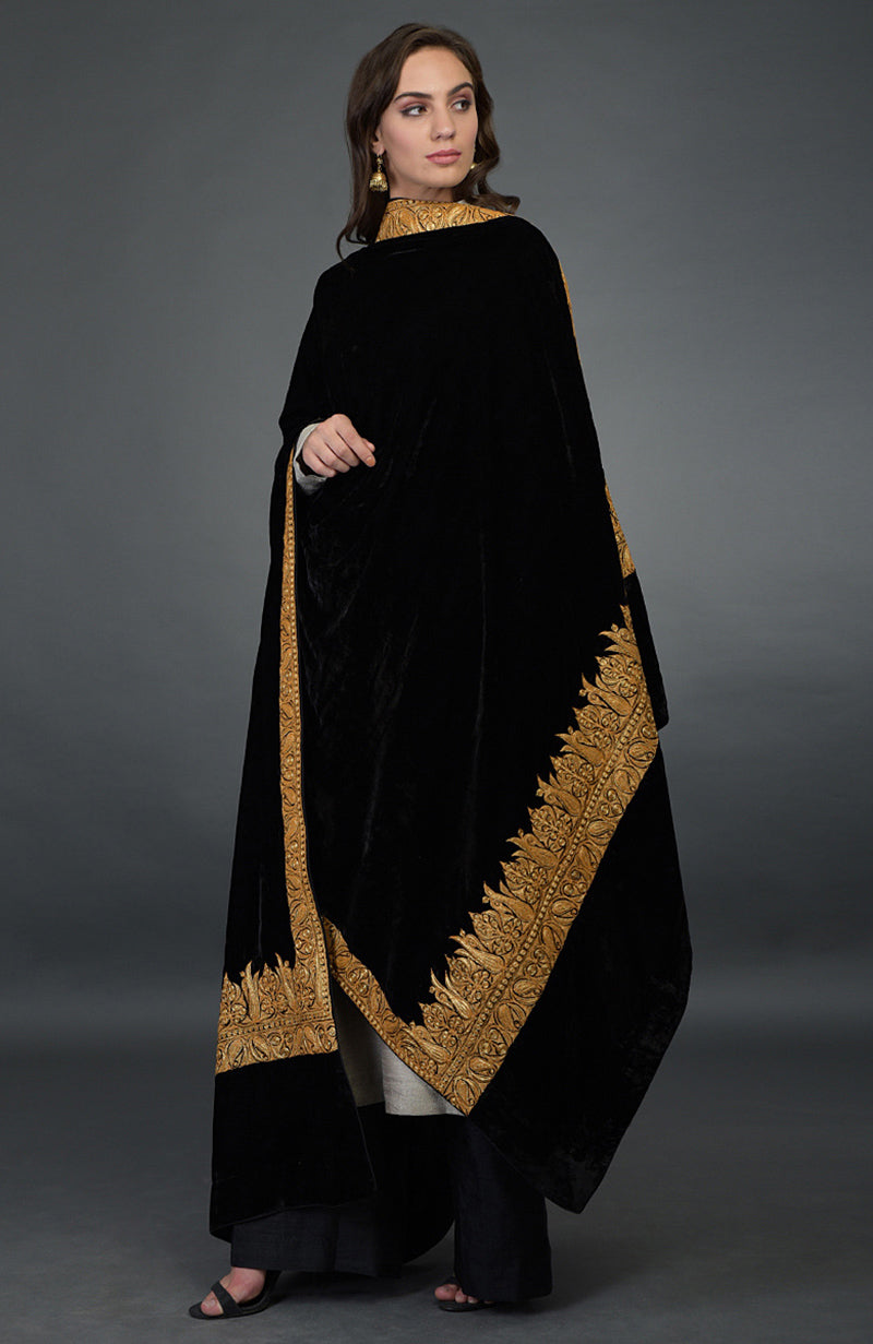 Woman in black velvet dupatta with gold embroidery, beige kurta, and black palazzo pants.