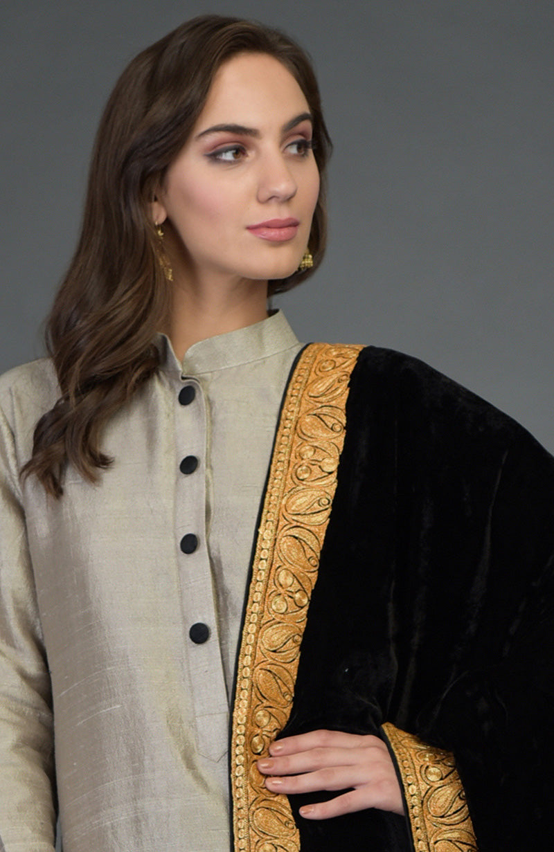 A woman models a beige kurta with black buttons and a black and gold embroidered dupatta.