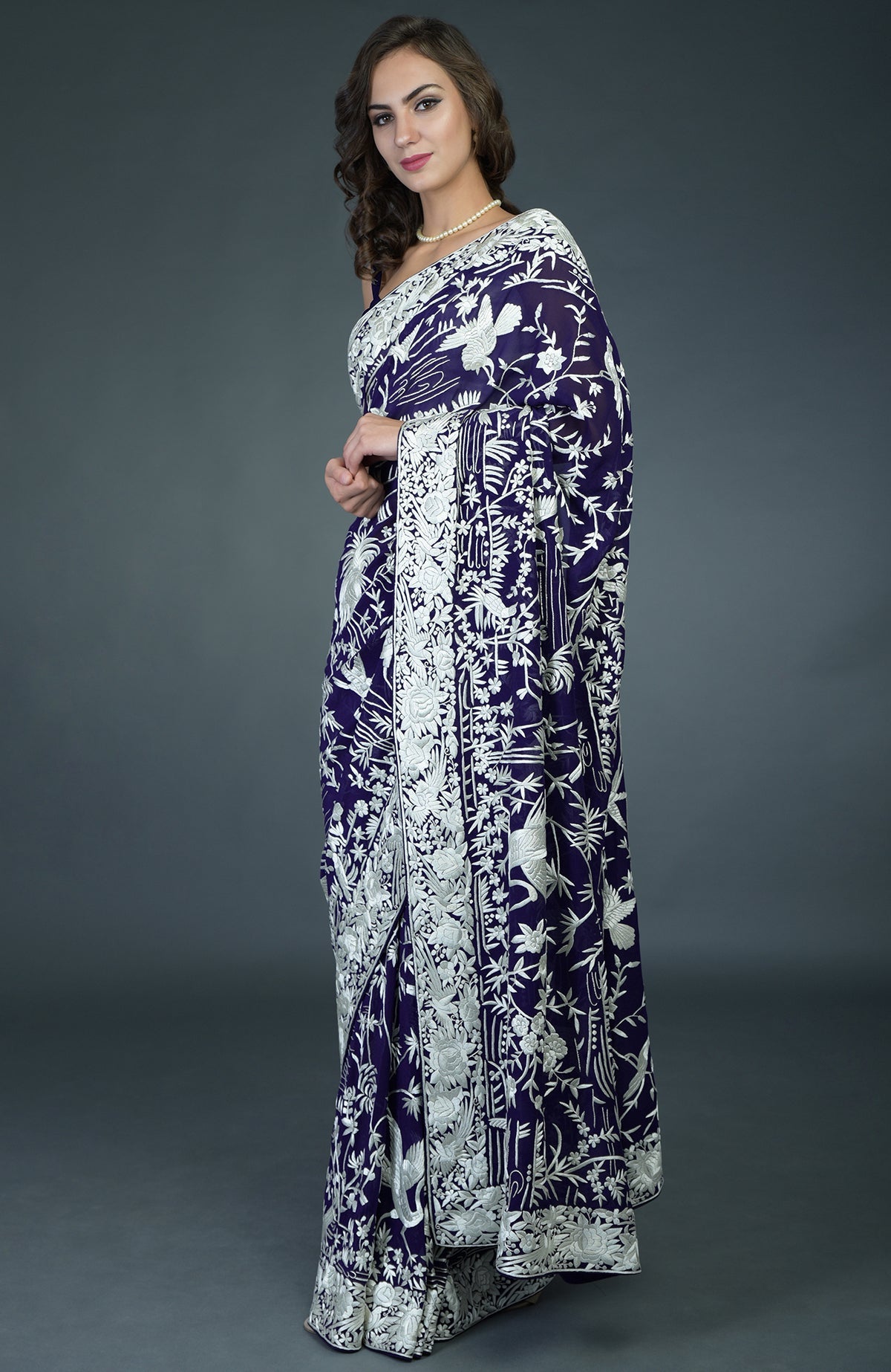 A woman models a navy blue Parsi Gara hand-embroidered saree with ivory bird and floral patterns.