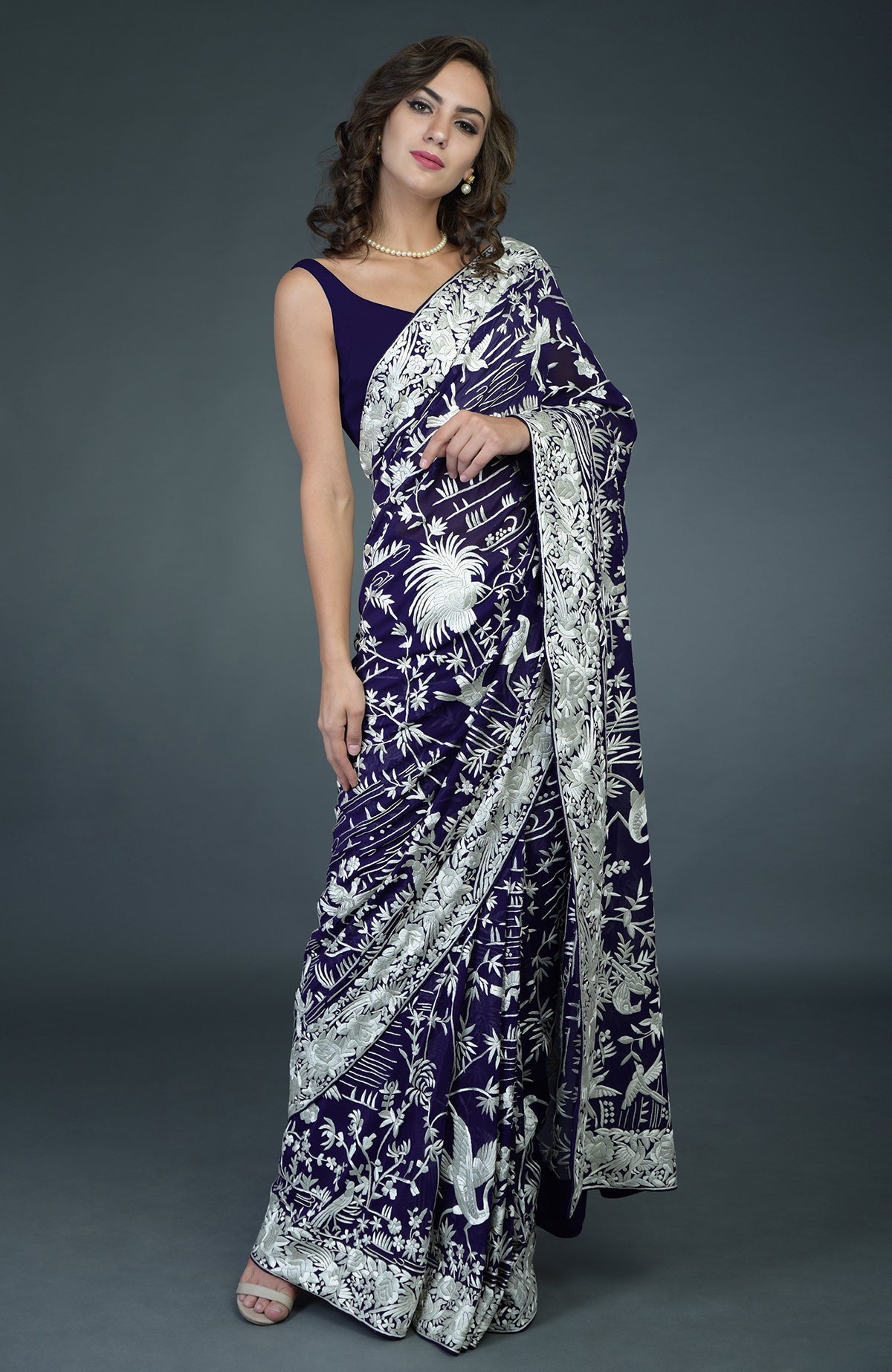 A woman models a navy blue Parsi Gara hand-embroidered saree with ivory bird and floral motifs.