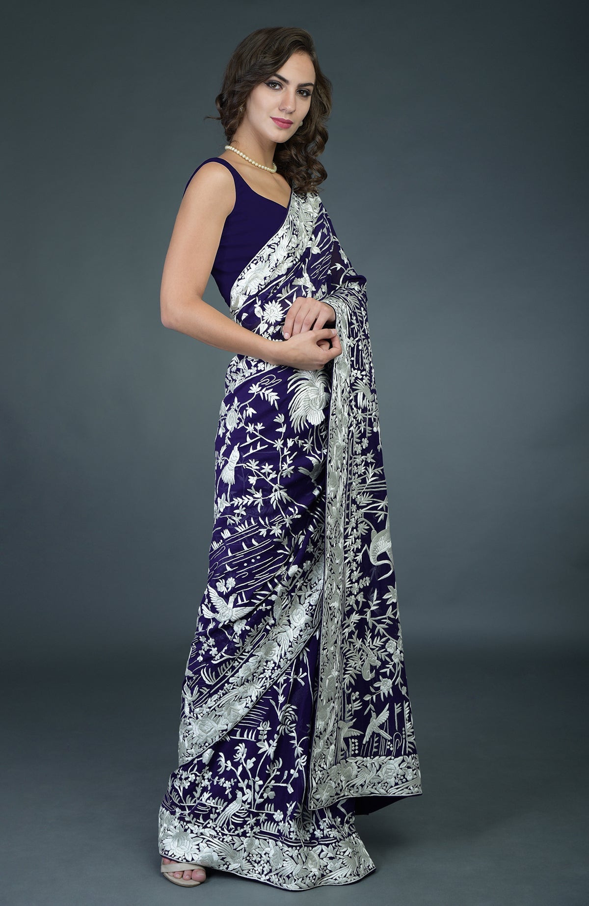 A woman models a navy blue Parsi Gara hand-embroidered saree with ivory bird and floral motifs.