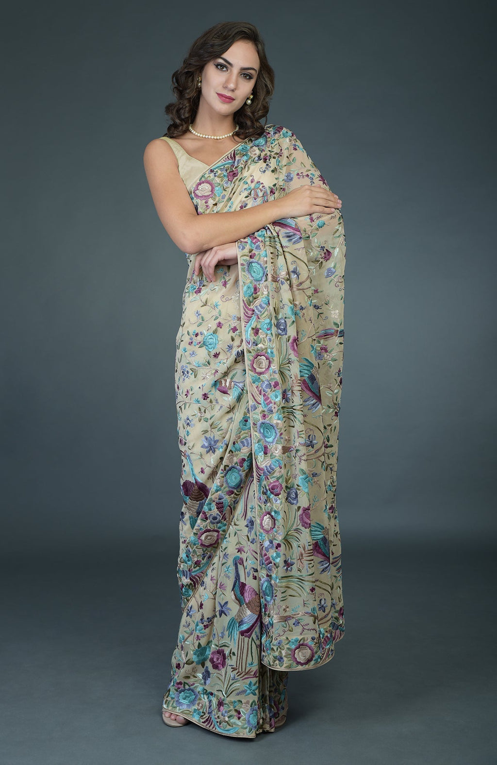 A woman models a fawn Parsi Gara hand-embroidered saree with floral and bird motifs.