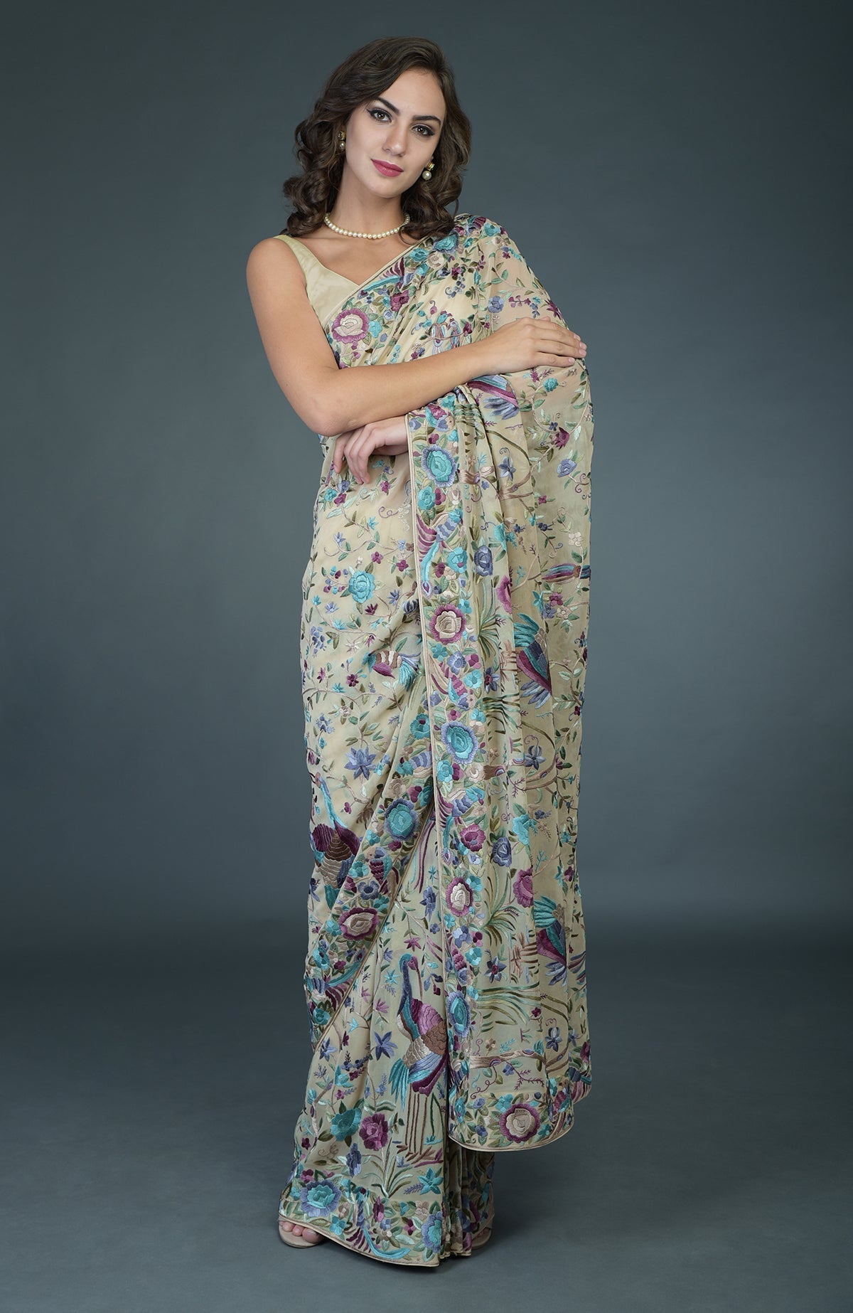 A woman models a fawn Parsi Gara hand-embroidered saree with floral and bird motifs.
