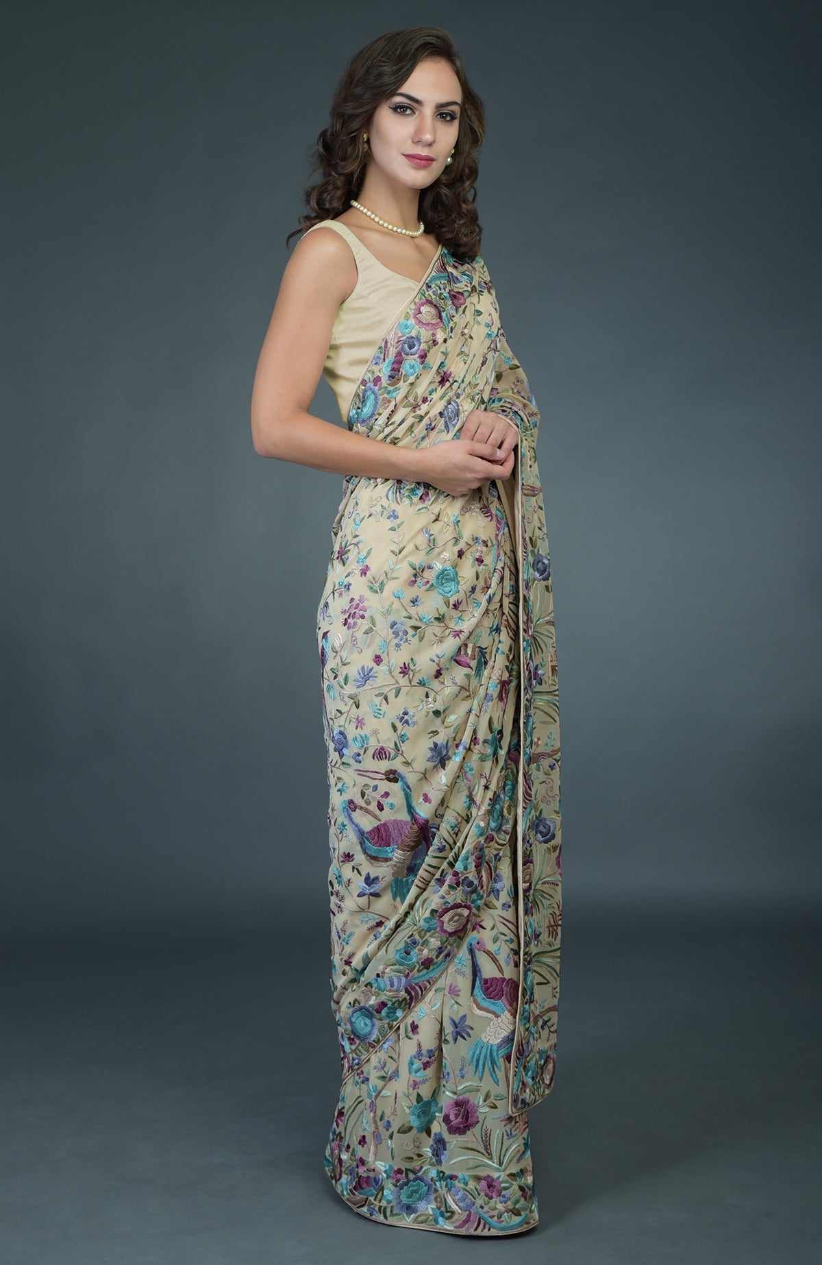 A woman models a fawn Parsi Gara hand-embroidered saree with birds and floral patterns.