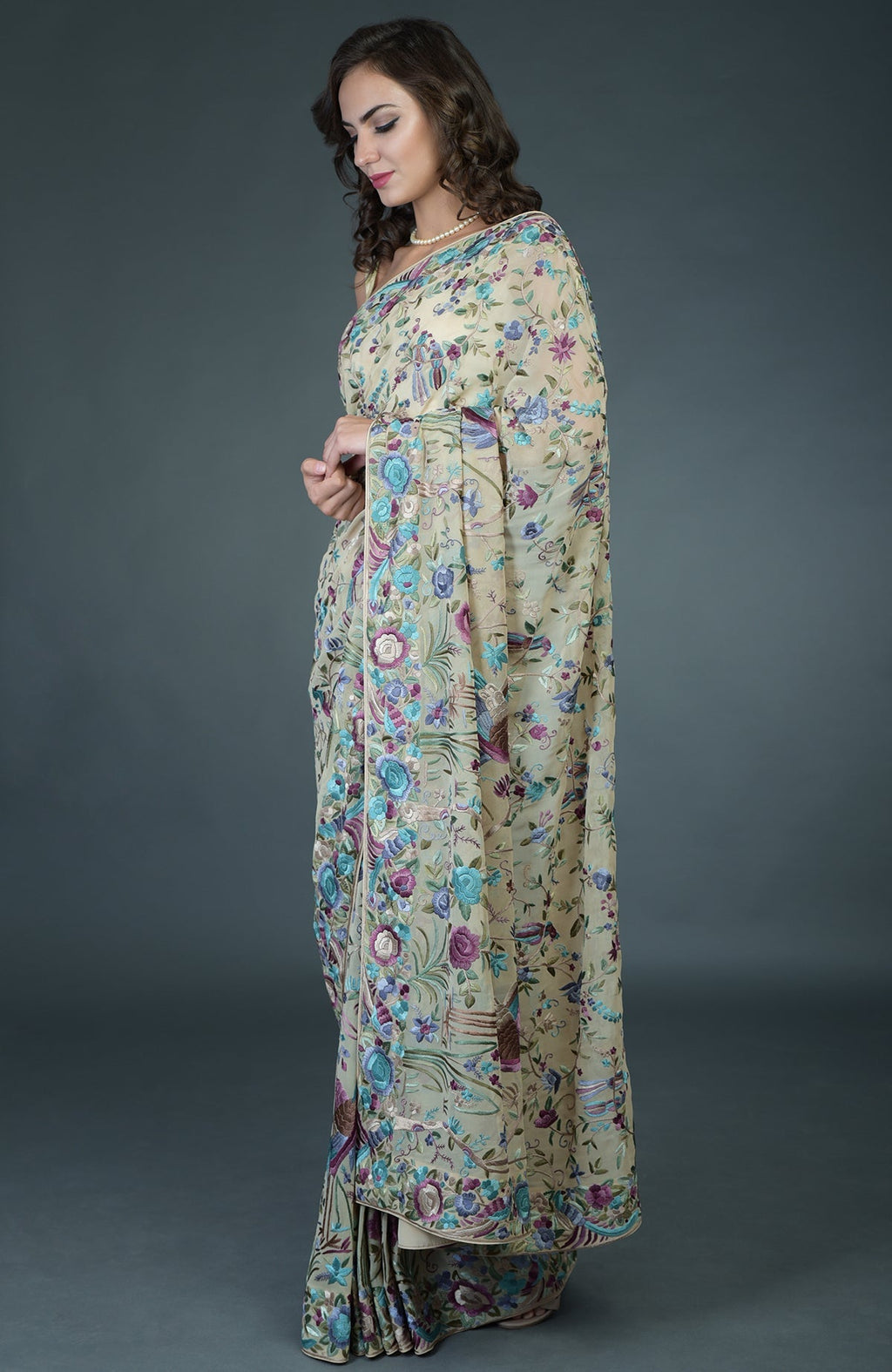 A woman models a fawn Parsi Gara hand-embroidered saree with floral and bird motifs.