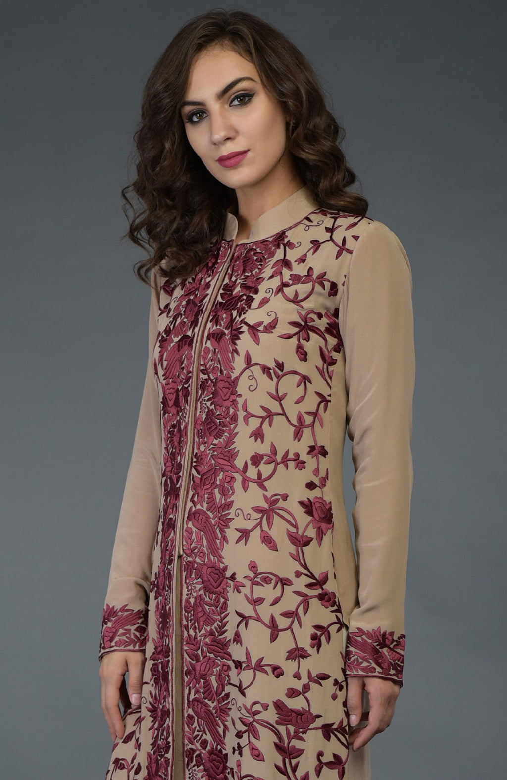 A woman models a fawn Parsi Gara jacket with wine floral and bird embroidery.