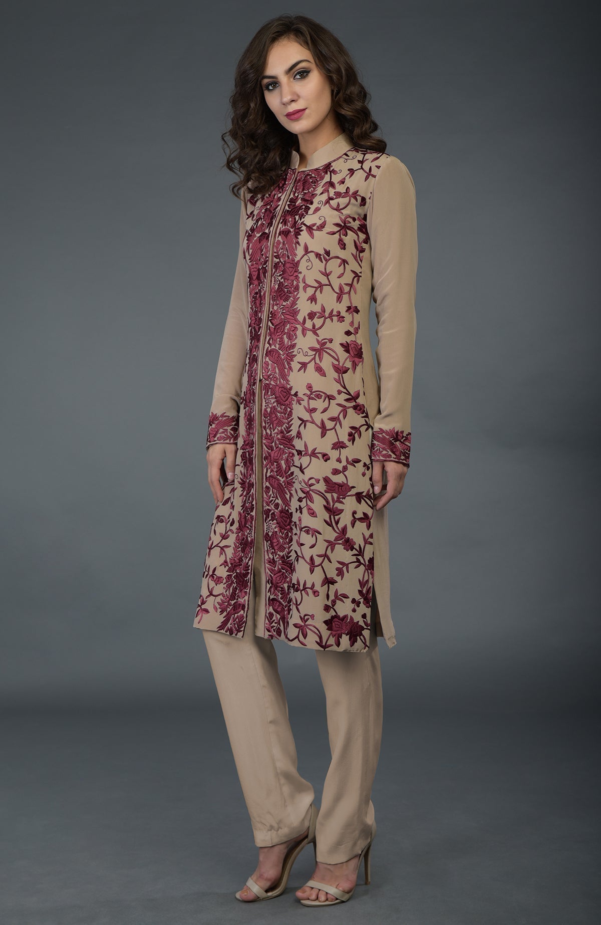 A woman models a fawn Parsi Gara jacket set with wine floral embroidery.
