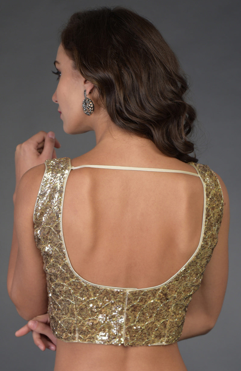 A woman models a gold sequin and zardozi hand-embroidered blouse with a deep U-back.