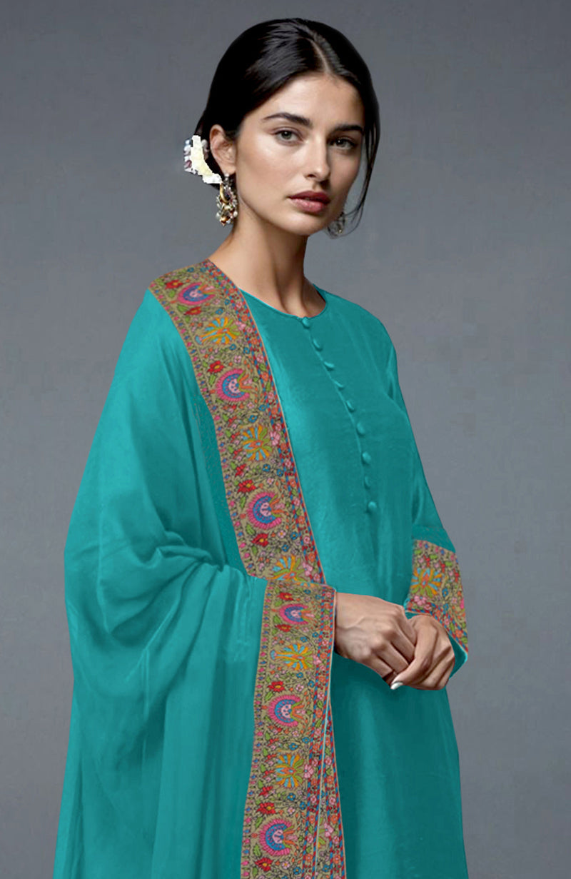 A woman models a viridian green suit with colorful Kashmiri hand embroidery.