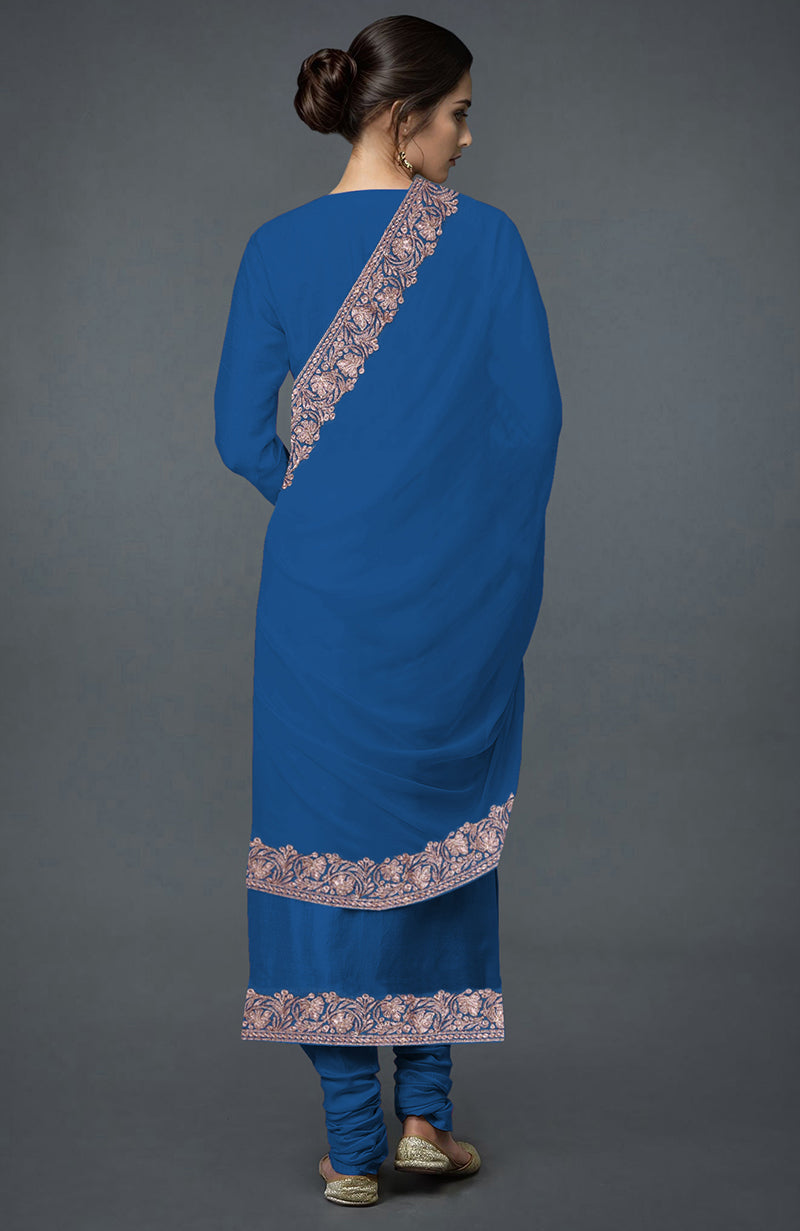 A woman from behind wears an imperial blue Kashmiri Tilla embroidered suit with gold shoes.