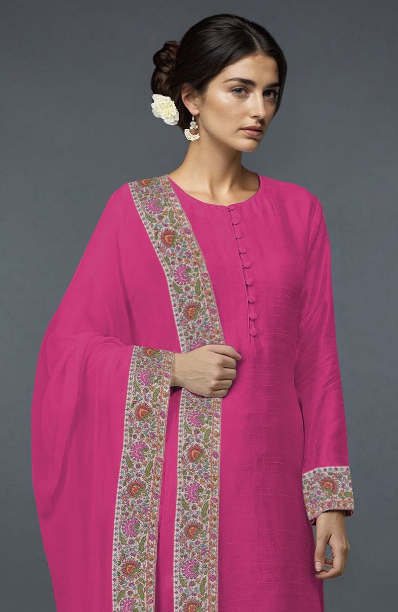 A woman models a pink raw silk suit with colorful Kashmiri embroidery on the dupatta and sleeves.
