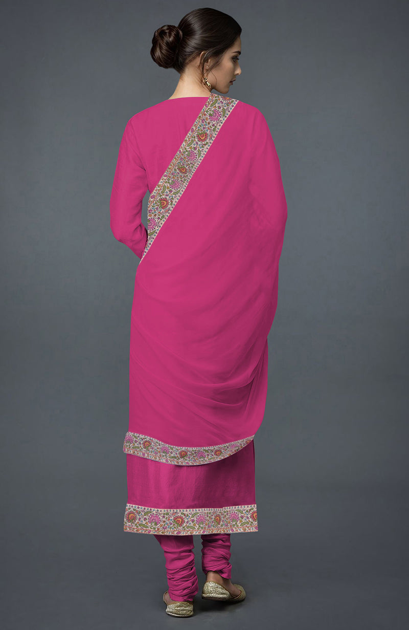 A woman from behind models a pink embroidered suit with a matching dupatta.