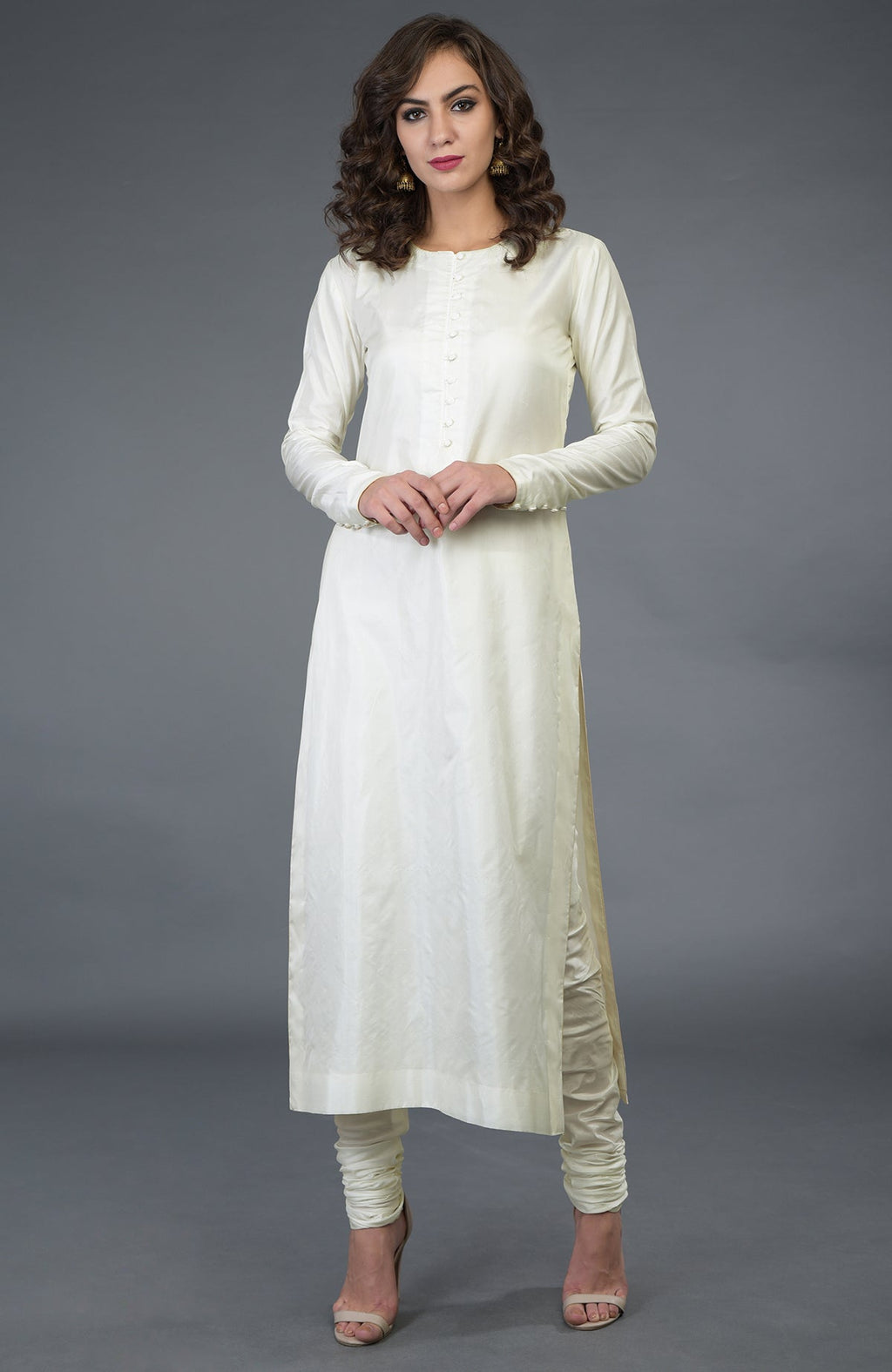 A woman models an ivory pure silk suit with a long kurta and churidar pants.