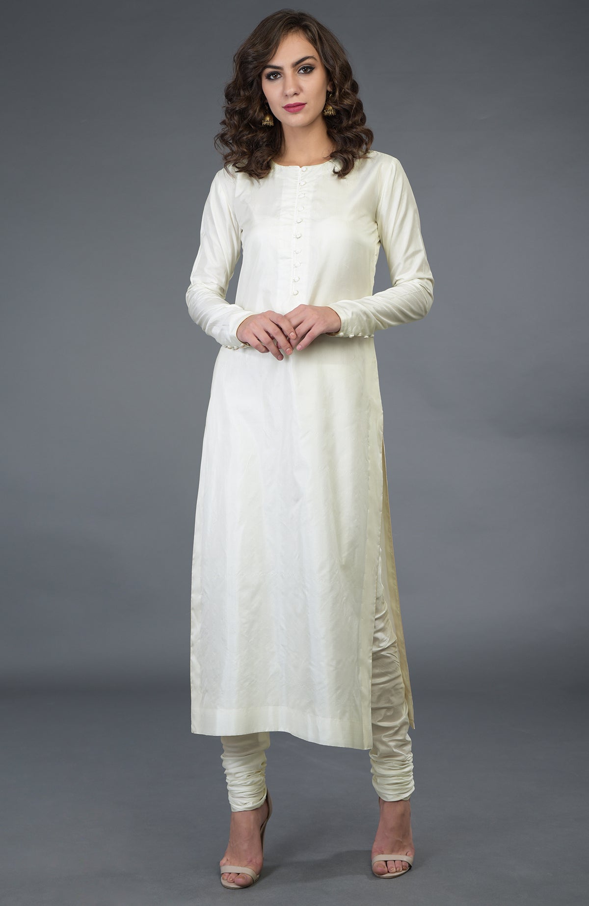 A woman models an ivory pure silk suit with a long kurta and churidar pants.