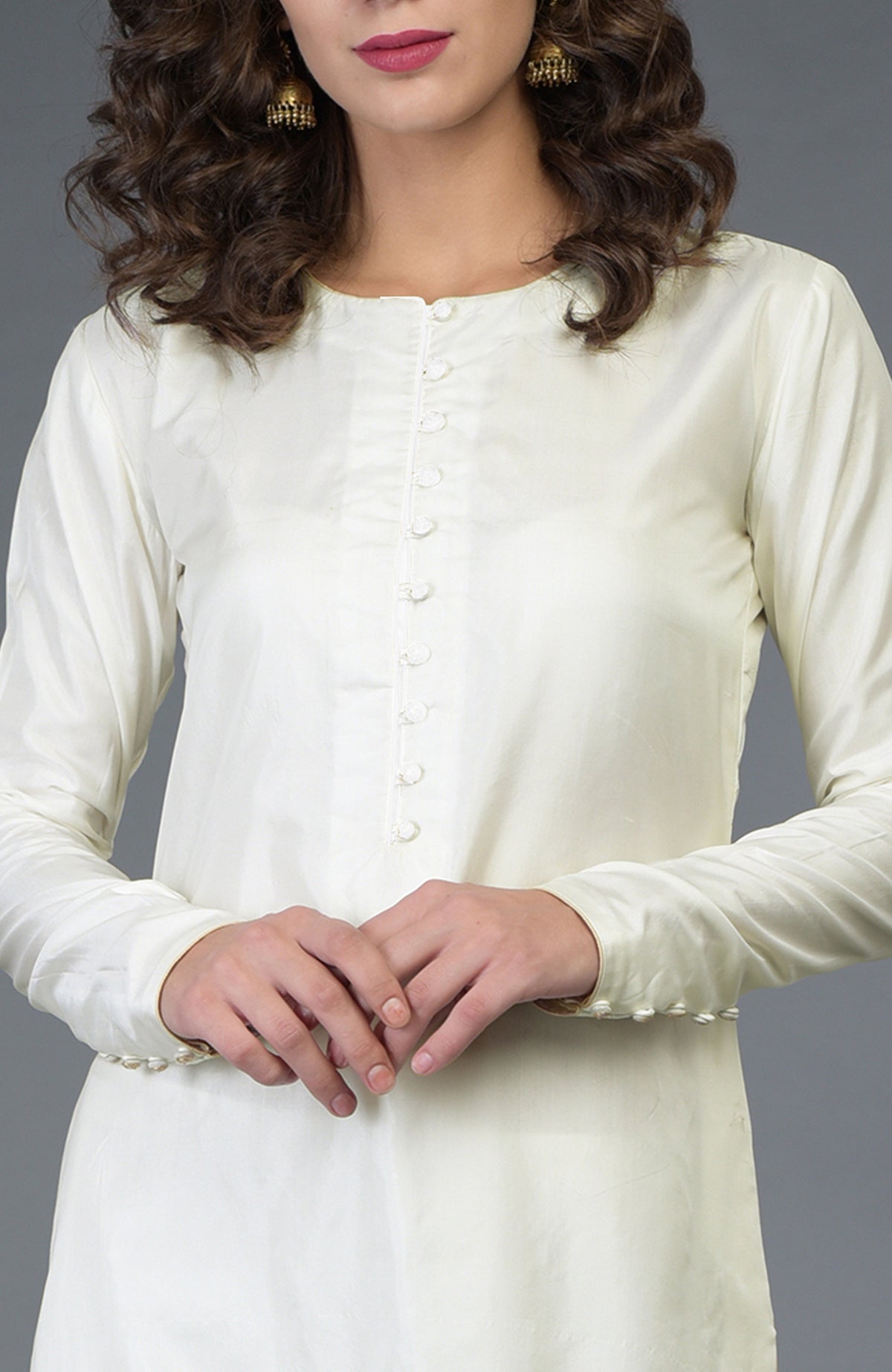 A woman models an ivory pure silk suit with a buttoned placket and decorative sleeve buttons.