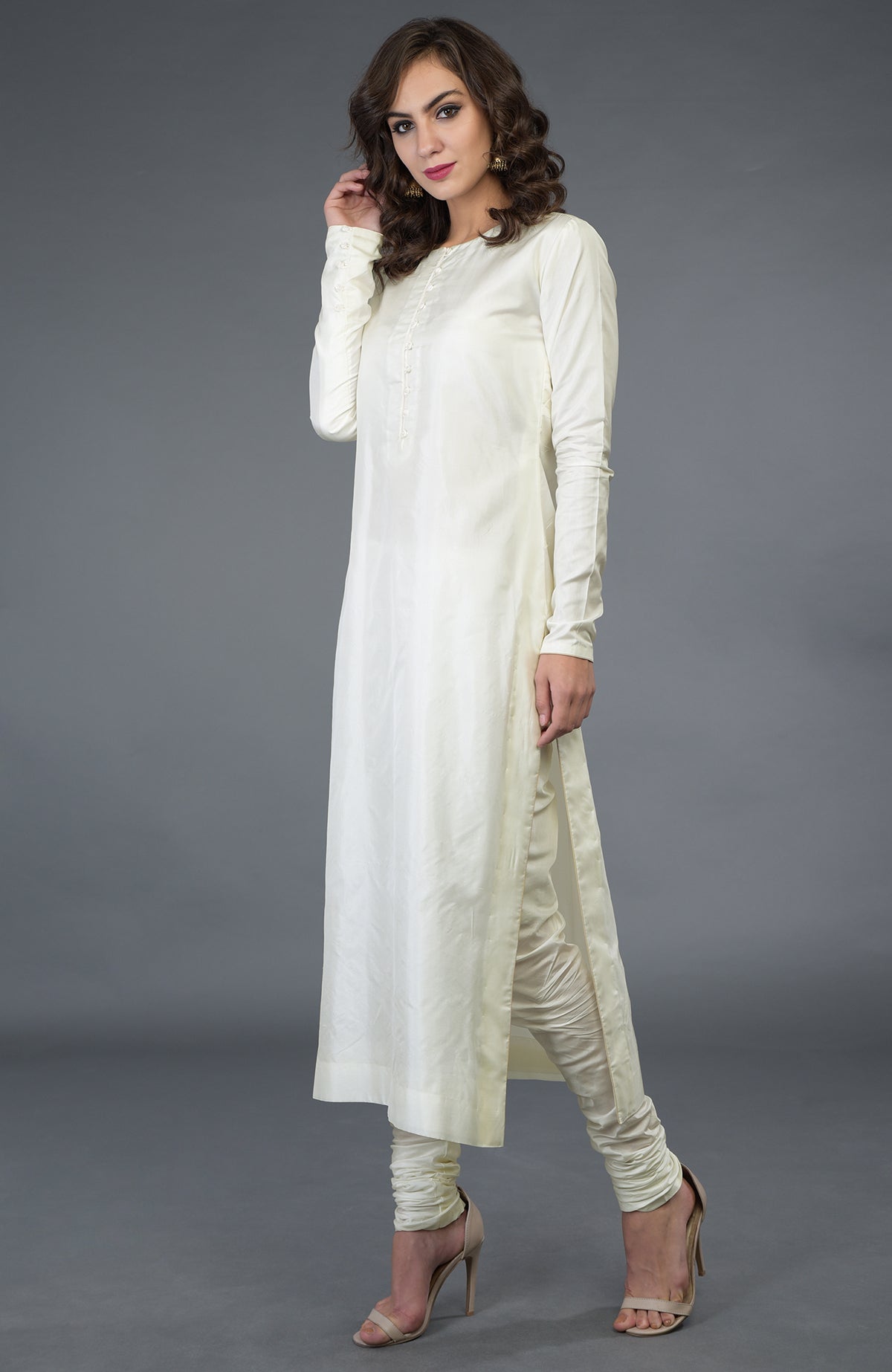 A woman models an ivory pure silk suit with a long kurta and churidar pants.