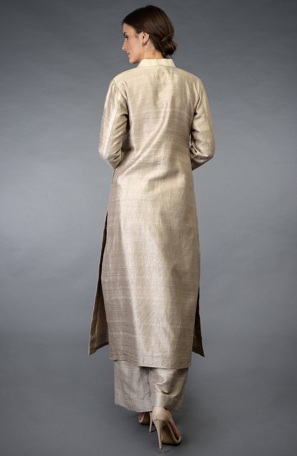 A woman models a beige raw silk suit with a long kurta and wide-leg pants.