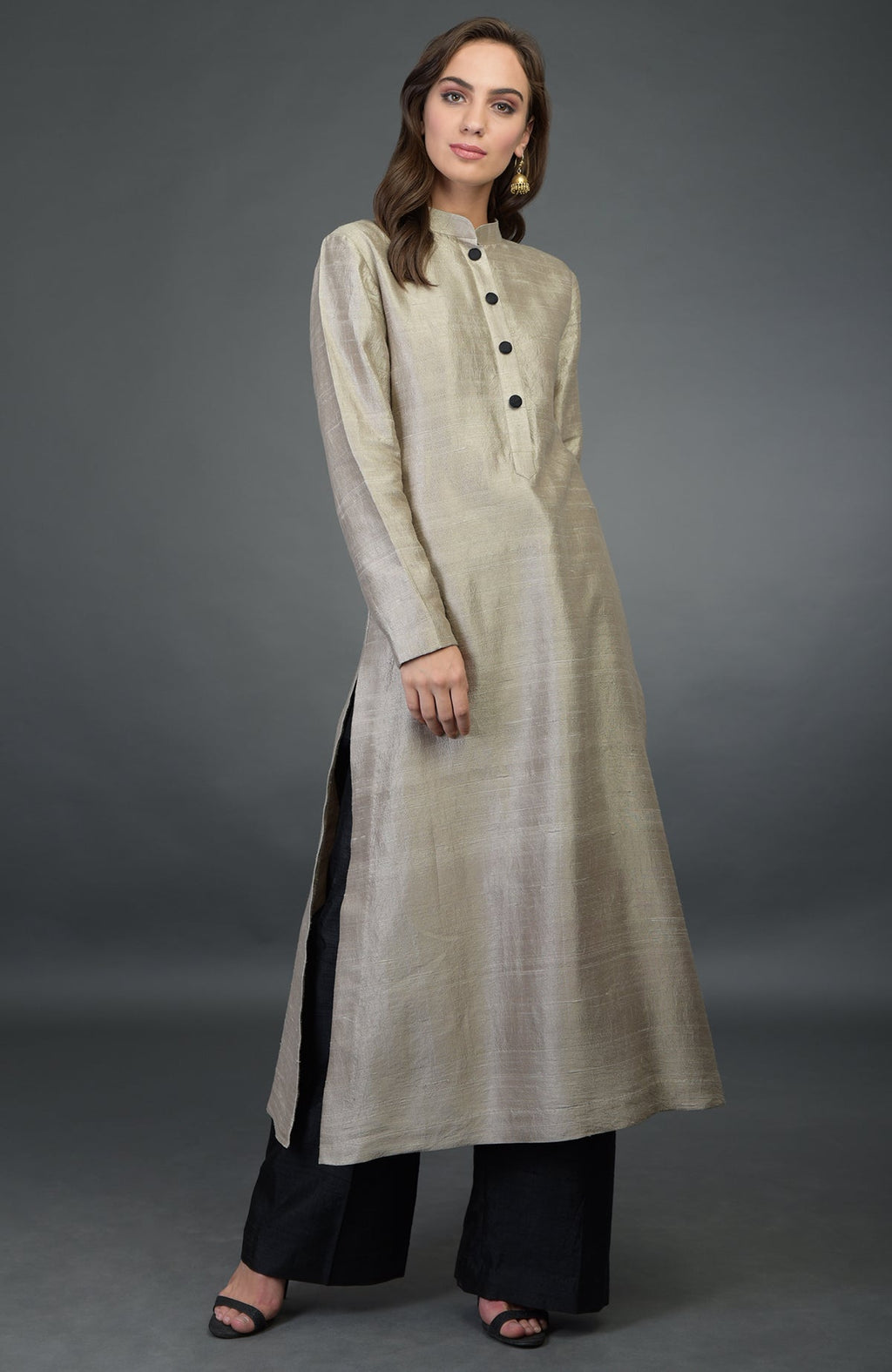 A woman models a beige raw silk kurta with black buttons and black wide-leg pants.