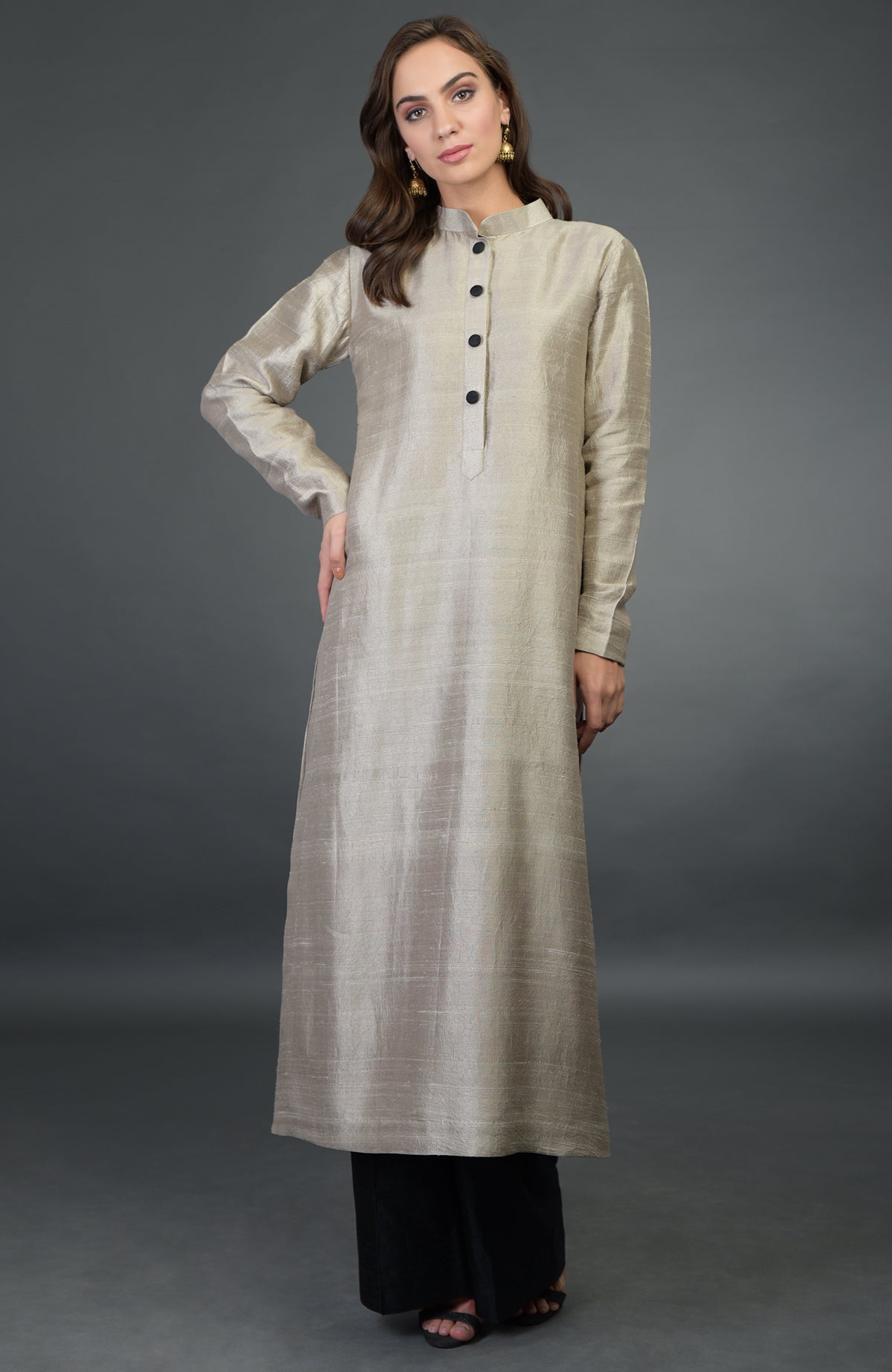 A woman models a beige raw silk kurta with black buttons and black wide-leg pants.