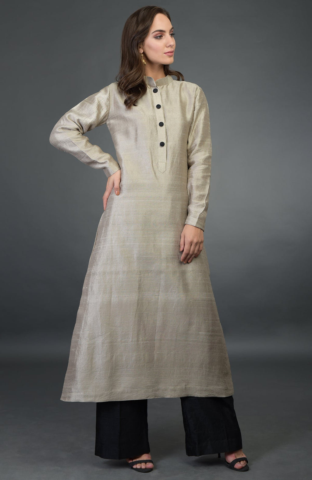 A woman models a beige raw silk suit with black buttons and black wide-leg pants.