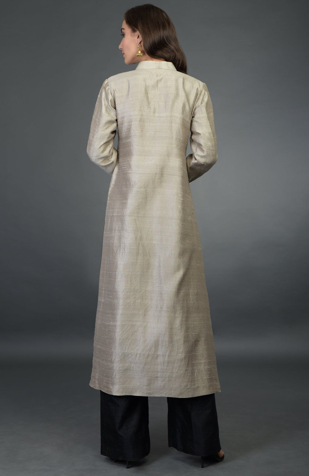 A woman from behind wears a beige raw silk kurta and black wide-leg pants.