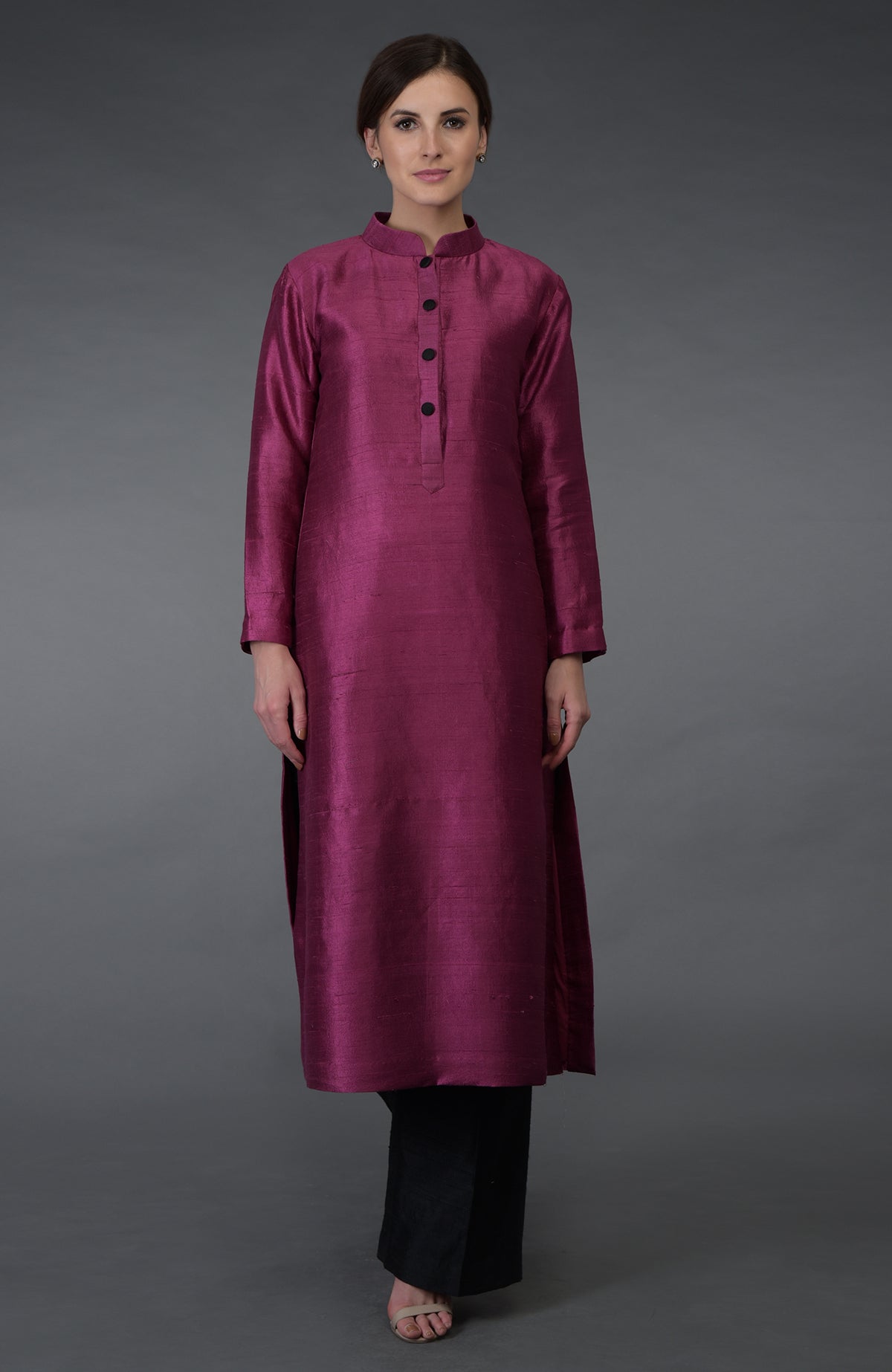 A woman models a magenta raw silk kurta with black buttons and black pants.