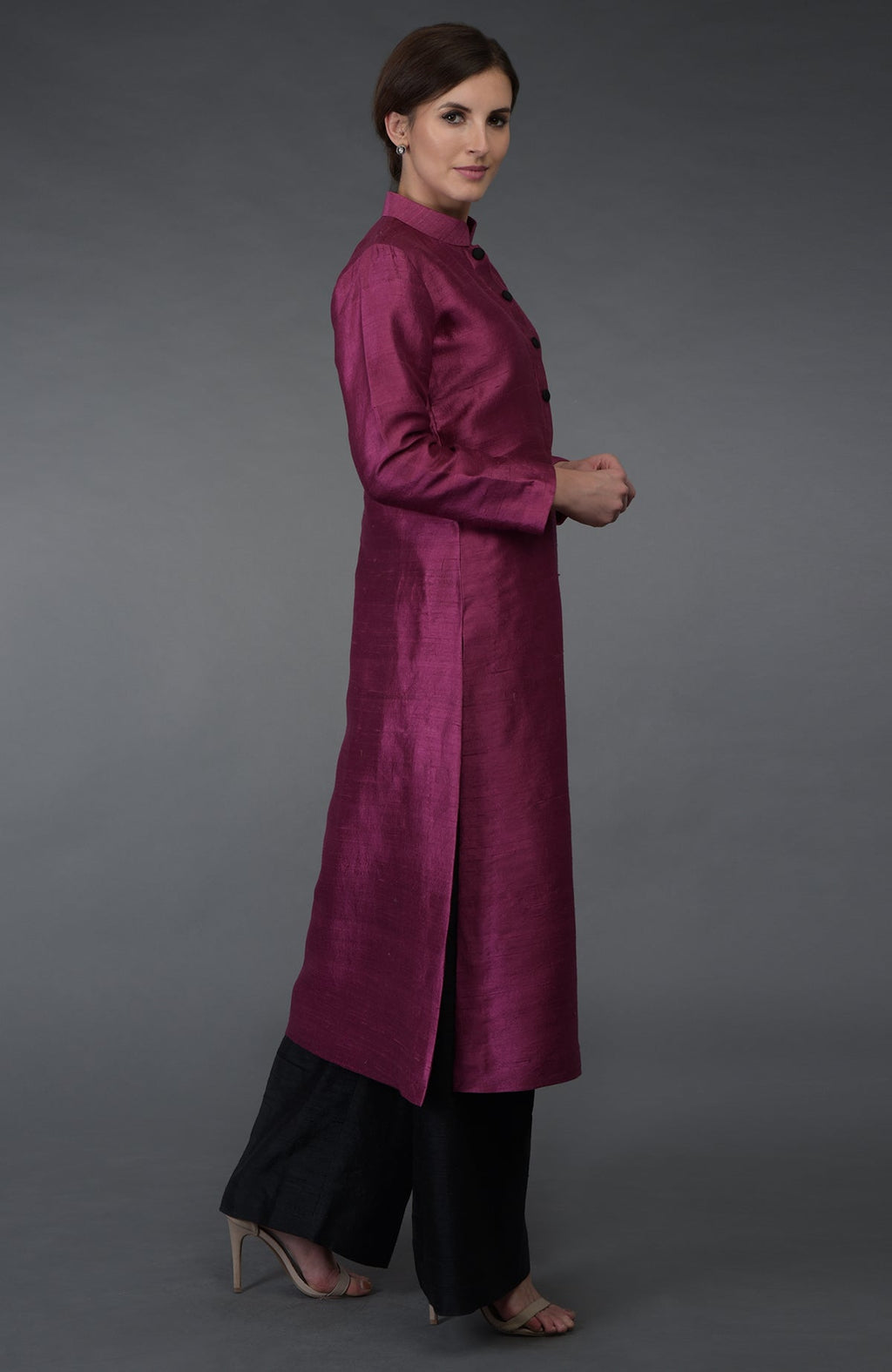 A woman models a peacock pink raw silk suit with black wide-leg pants.