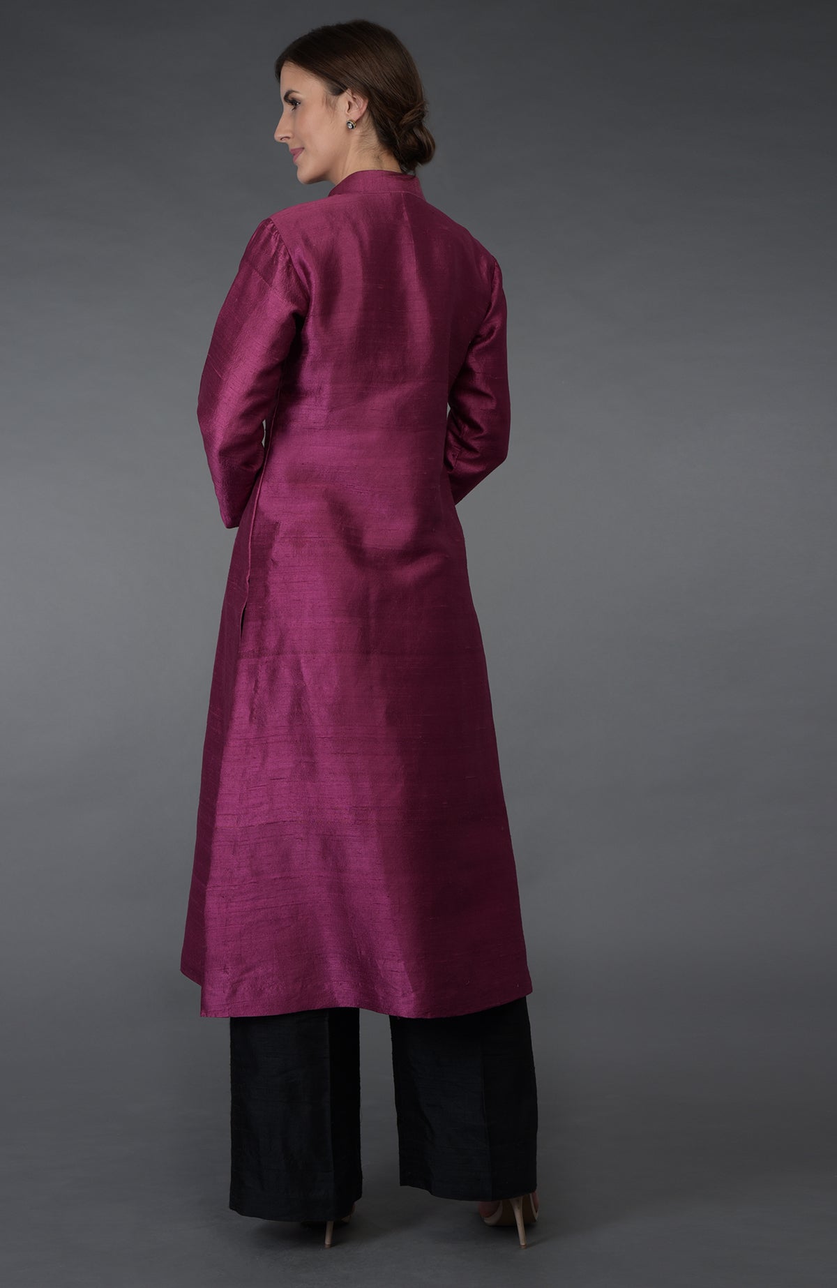 A woman in a peacock pink raw silk kurta and black wide-leg pants.