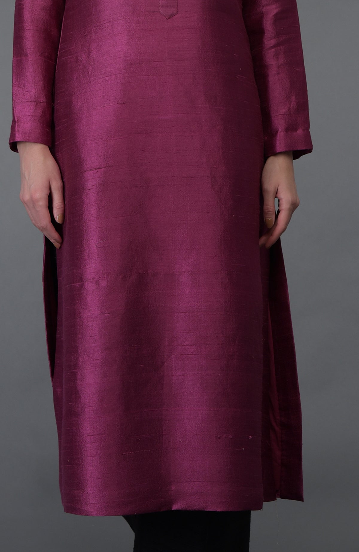 A person wears a long, magenta raw silk kurta with full sleeves.