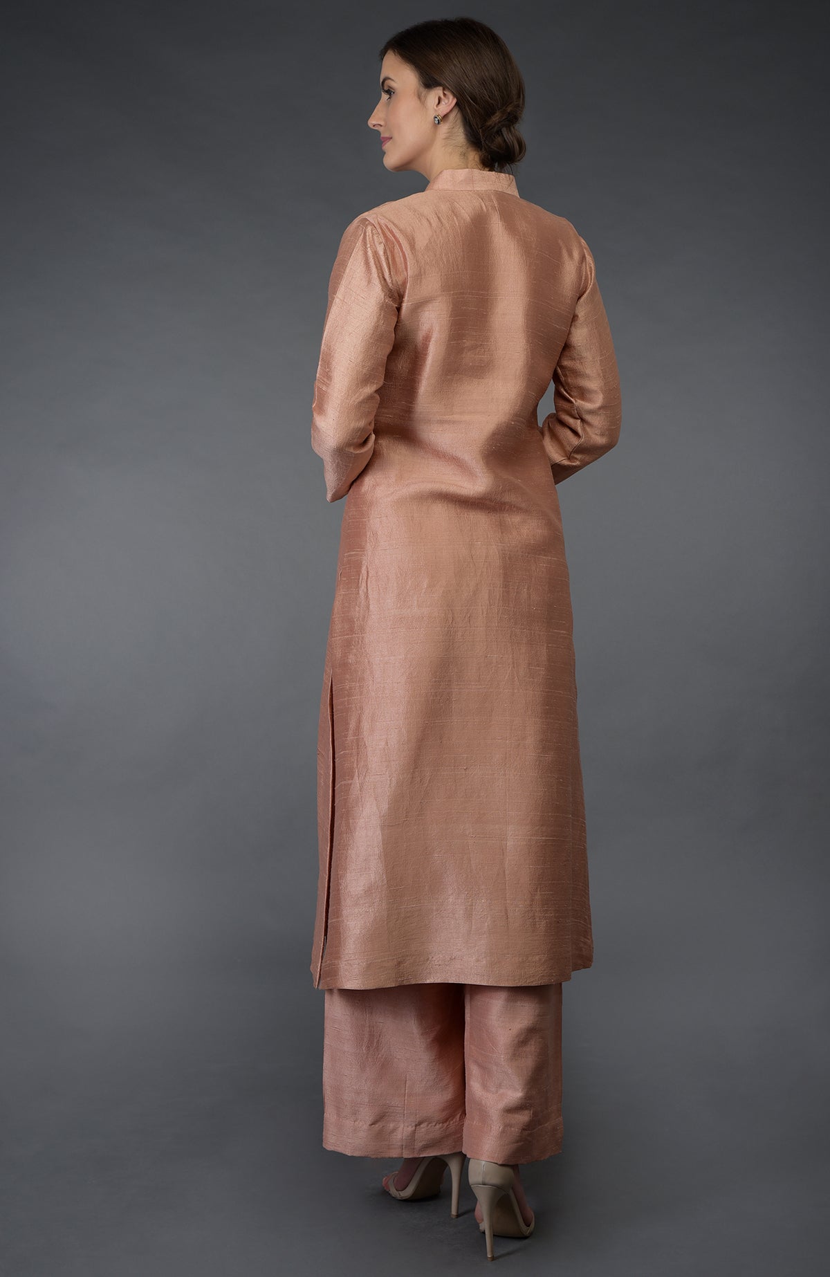 A woman models a pressed rose raw silk suit with a long kurta and palazzo pants.